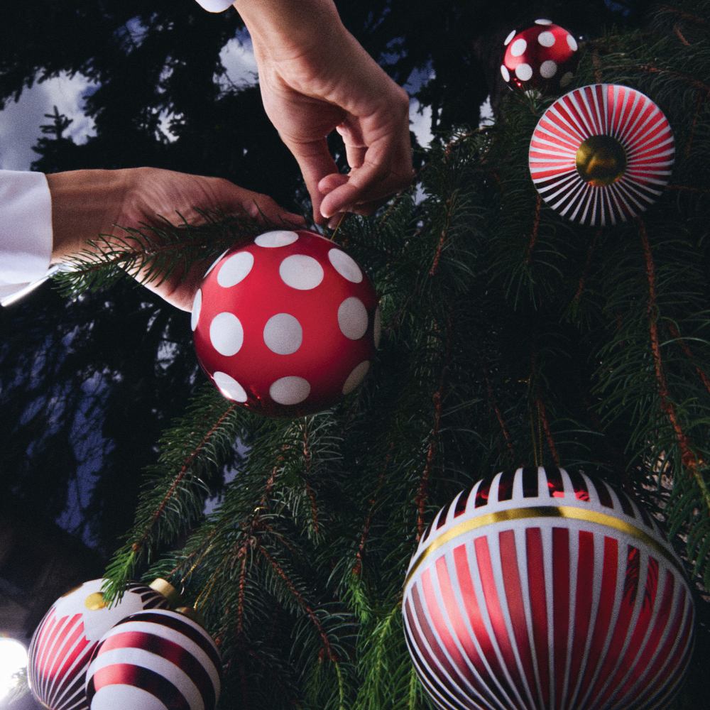 Hand dekoriert Weihnachtsbaum mit Alessi NZ04 2 Delight Weihnachtskugeln in Rot und Weiß.