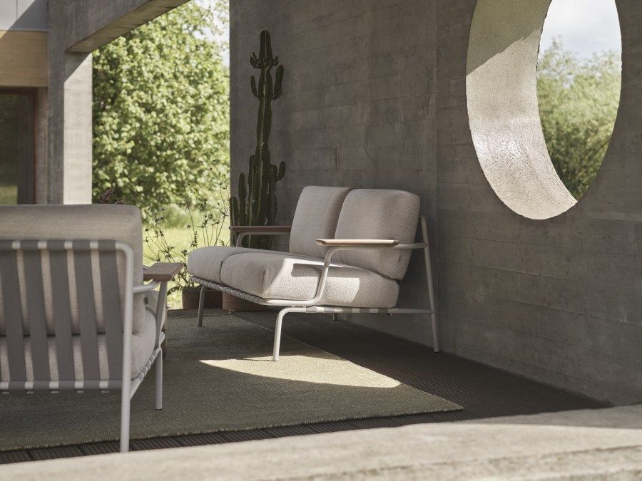 Muuto Settle Outdoor Sofa: Modernes 2-Sitzer Gartensofa mit hellgrauem Bezug und minimalistischem Design auf Terrasse.