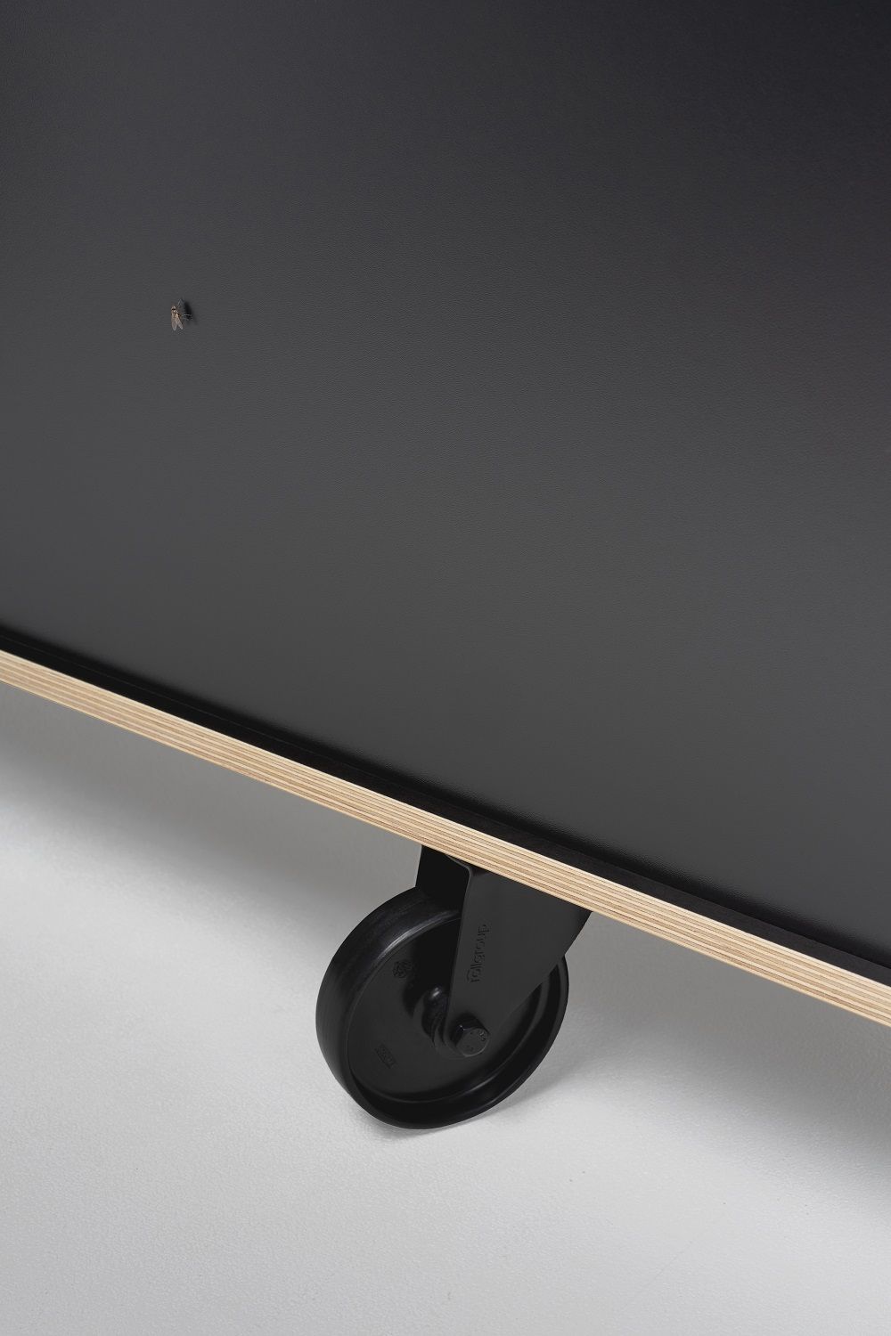 Detailaufnahme vom Rockboard Sideboard von Nils Holger Moormann, Fokus auf schwarze Rollen und Multiplex-Kante.
