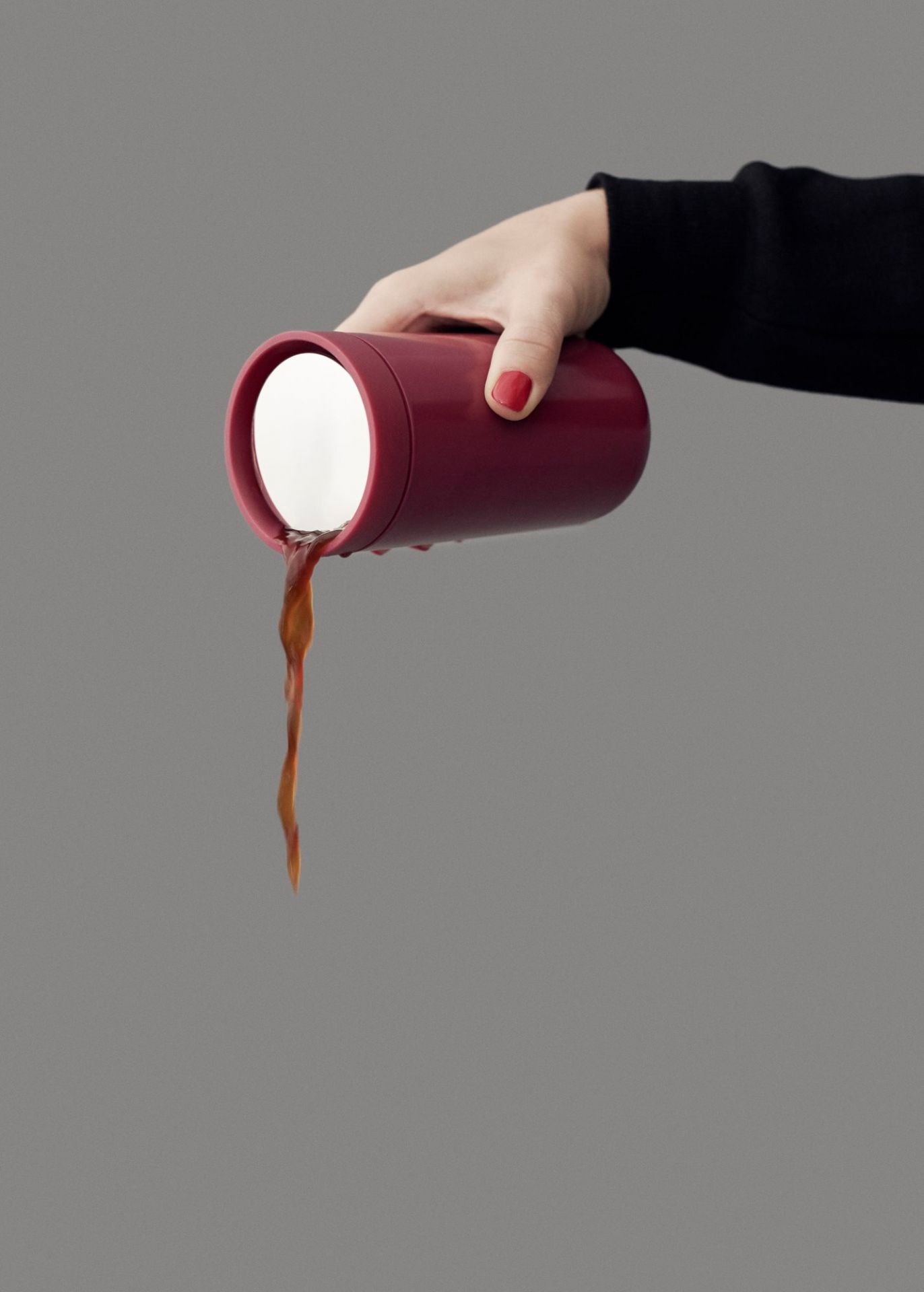 Hand hält roten Stelton To Go Click Thermobecher und gießt Kaffee aus, isolierter Reisebecher.