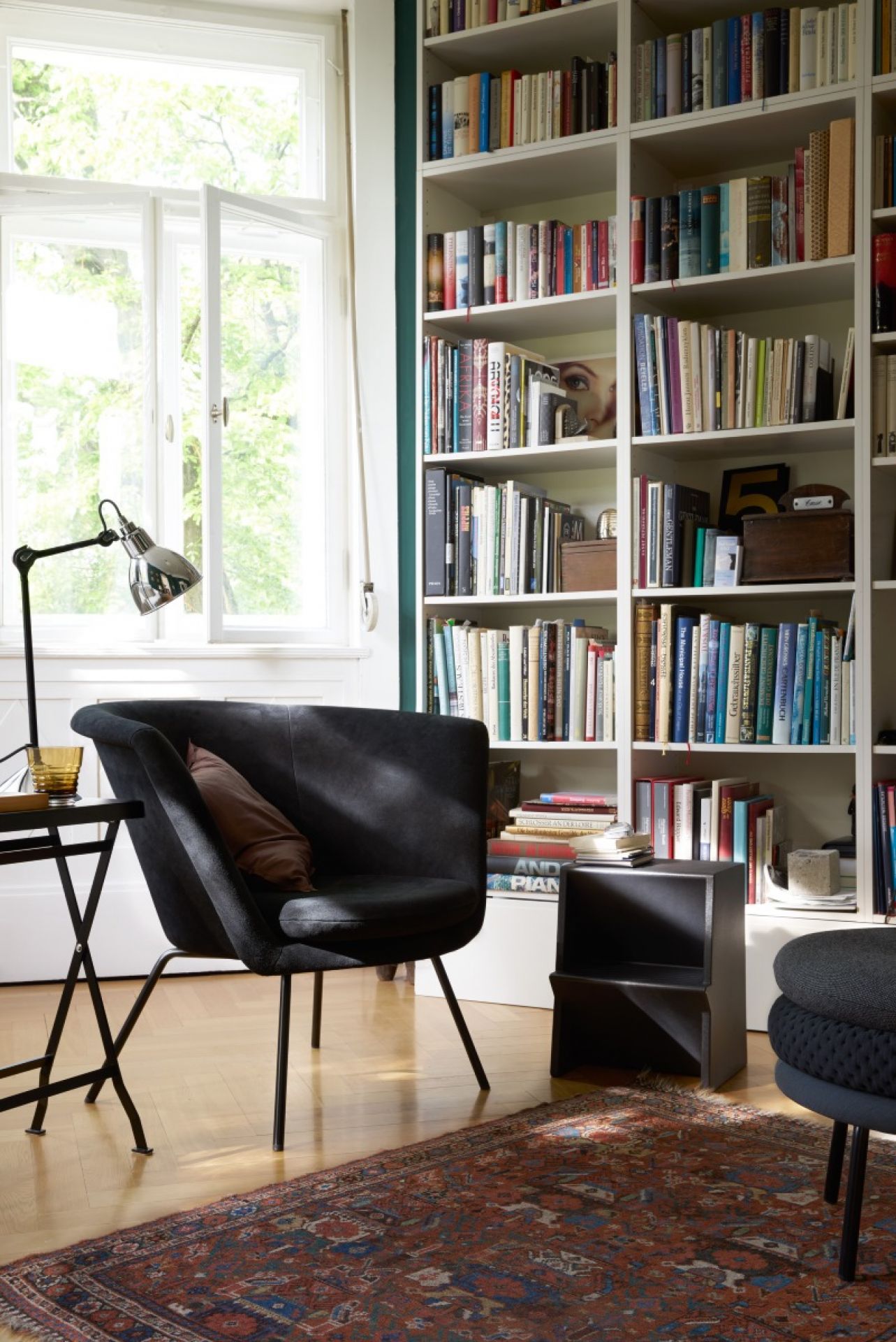 Schwarzer H57 Sessel von Richard Lampert in stilvollem Wohnzimmer mit Bücherregal und Teppich.