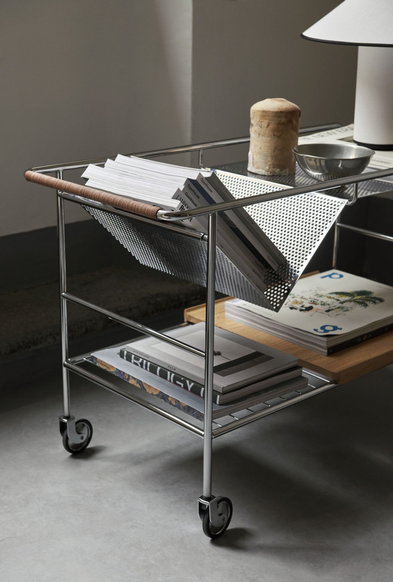 Alima NDS1 Rollwagen von AndTradition aus Stahl mit Magazinablage und Holzablage, gefüllt mit Büchern.