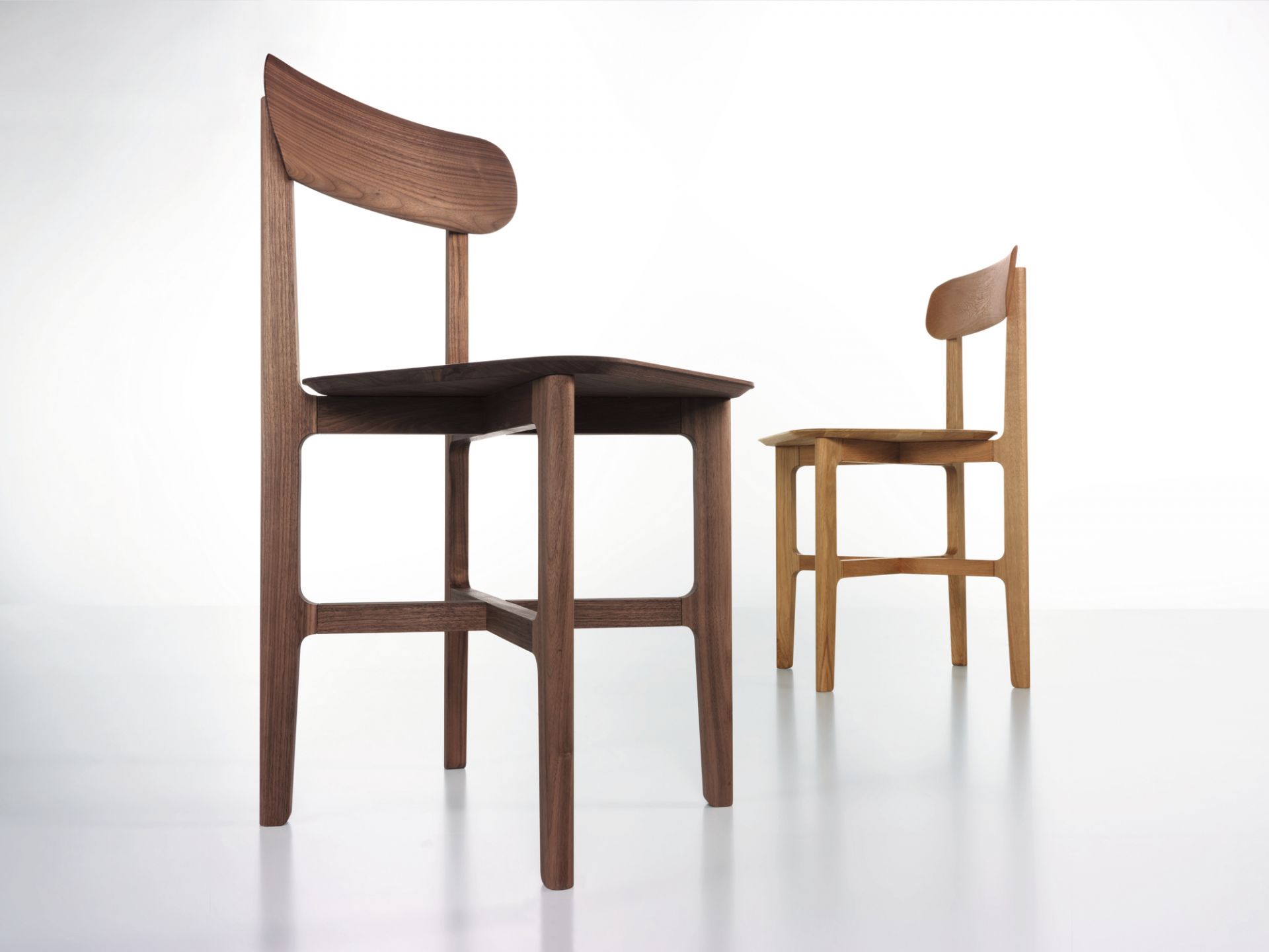 1.3 Chair Holzstuhl Zeitraum: Zwei moderne Holzstühle in Walnuss und Eiche auf weißem Hintergrund.