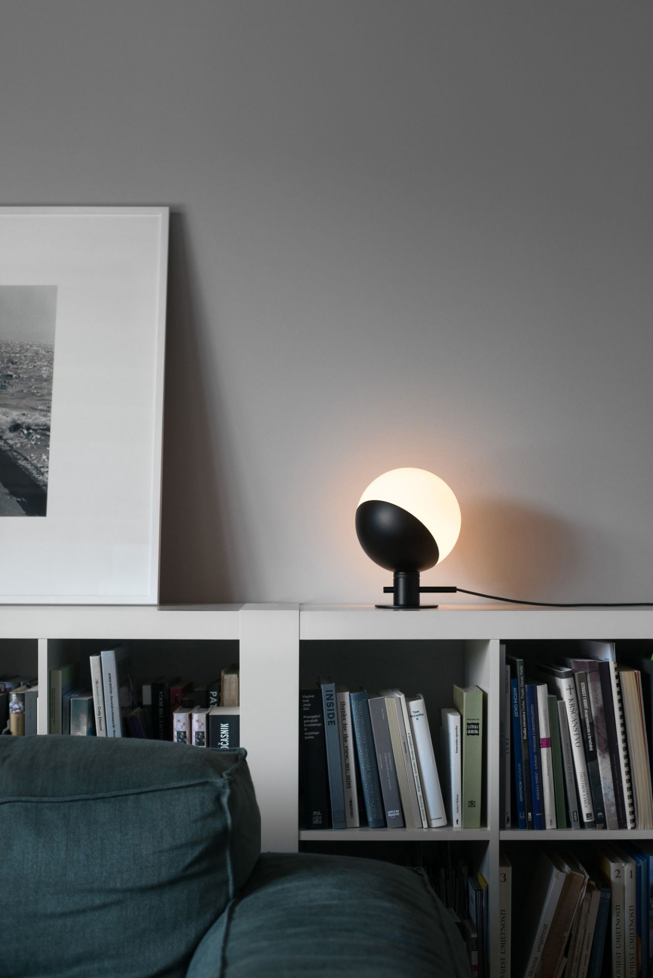 Baluna Tischleuchte von Grupa auf Regal mit Büchern. Moderne Lampe, schwarz-weiß, für Wohnzimmer.