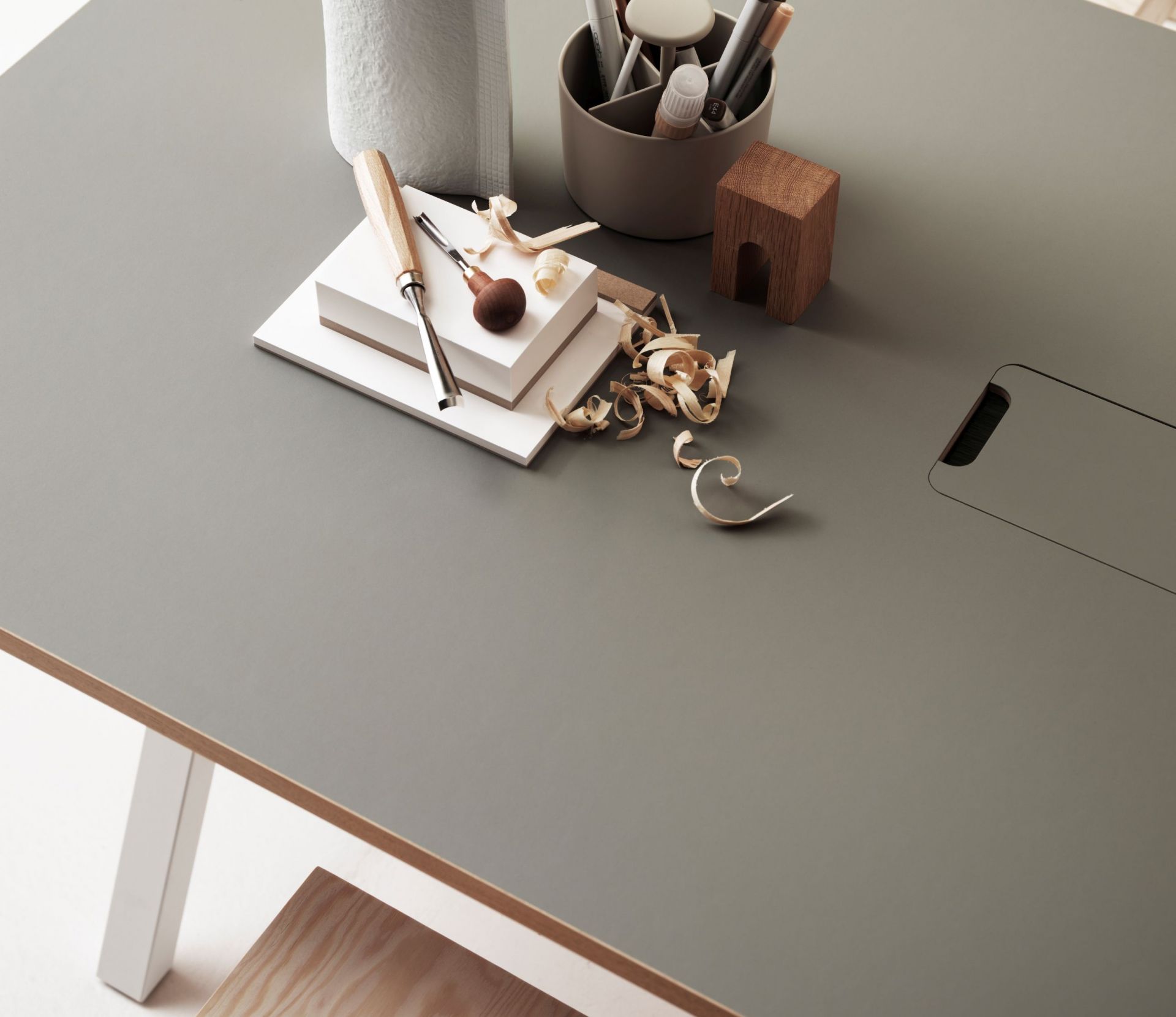 Works Schreibtisch Fix B140cm von String Furniture in Grau mit Werkzeugen und Hobelspänen für kreatives Arbeiten.