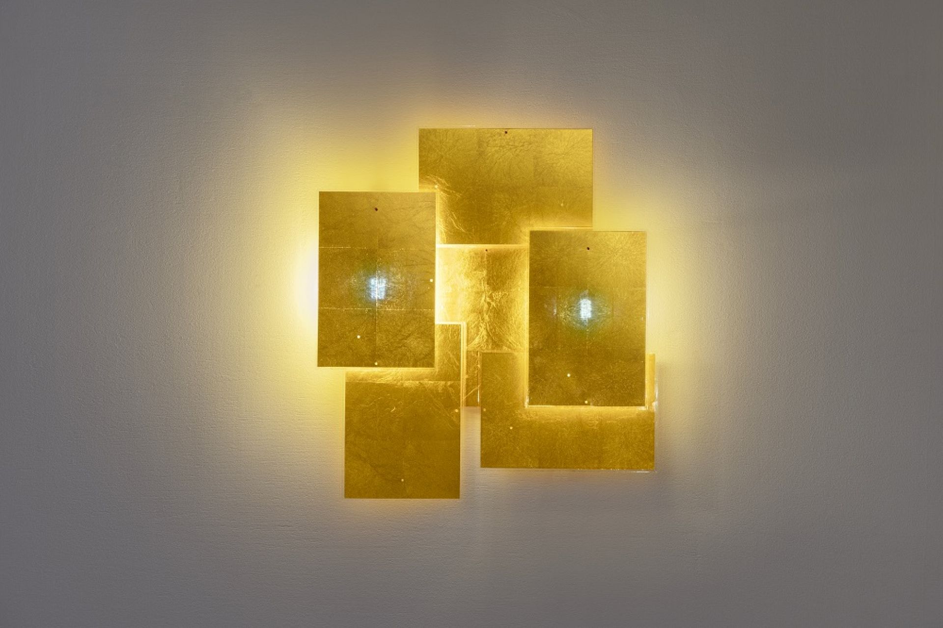 Nahaufnahme der 24 Karat Blau Wandleuchte von Ingo Maurer, goldene Quadrate an einer Wand.