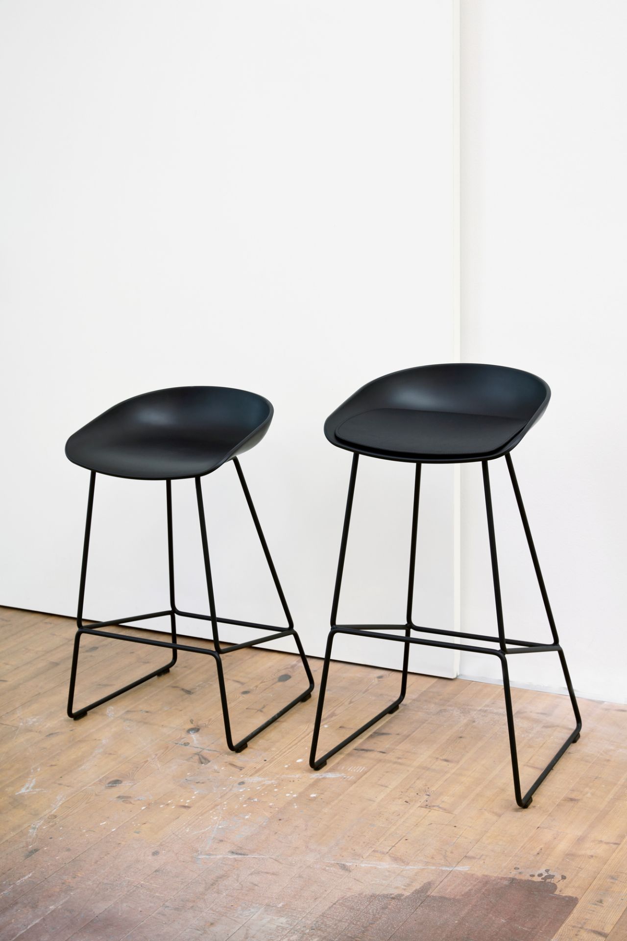 Zwei schwarze About a Stool AAS 38 Barhocker von Hay mit minimalistischem Design vor weißem Hintergrund.