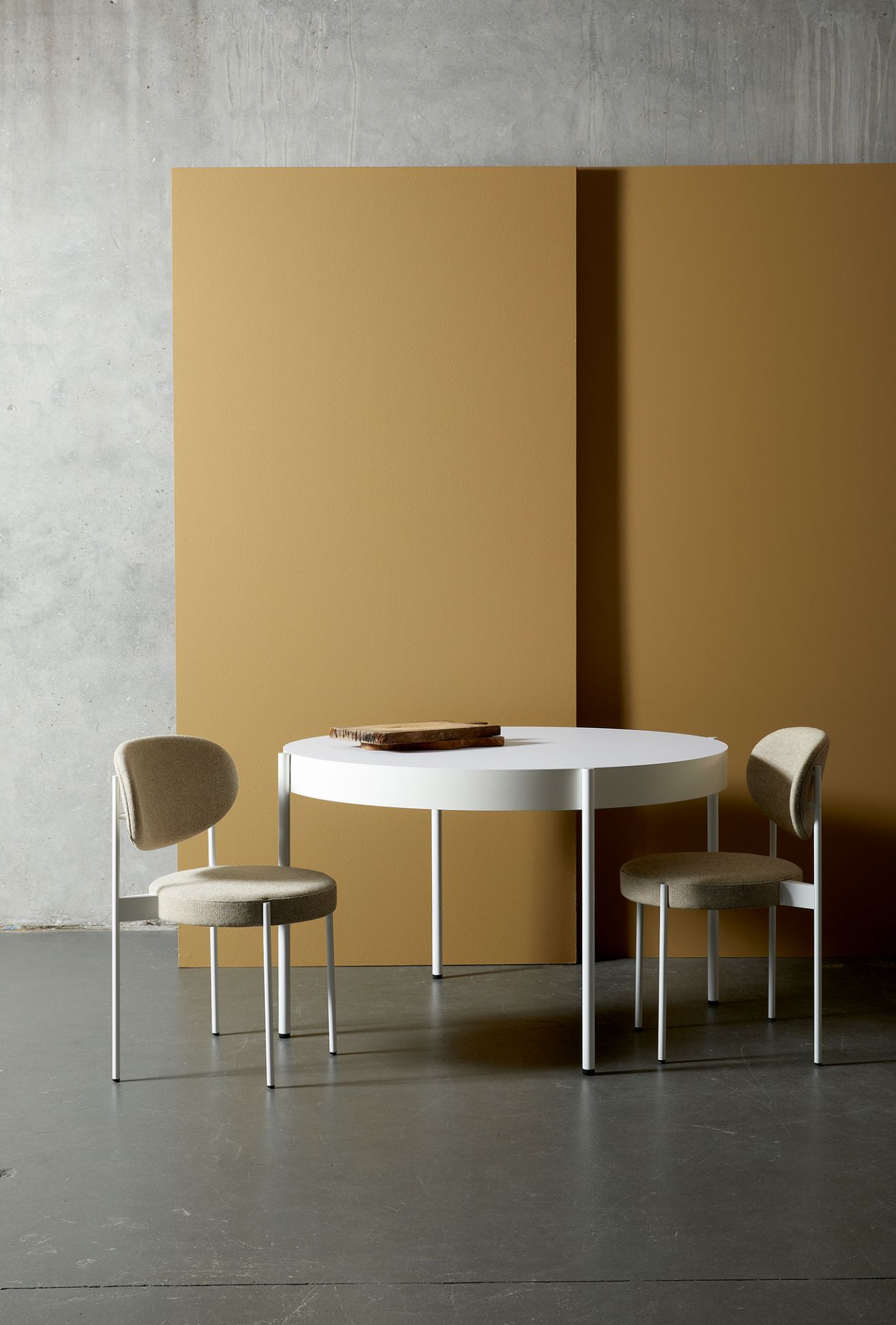 Verpan Series 430 Tisch mit zwei Stühlen in minimalistischem Design vor farbigem Hintergrund.