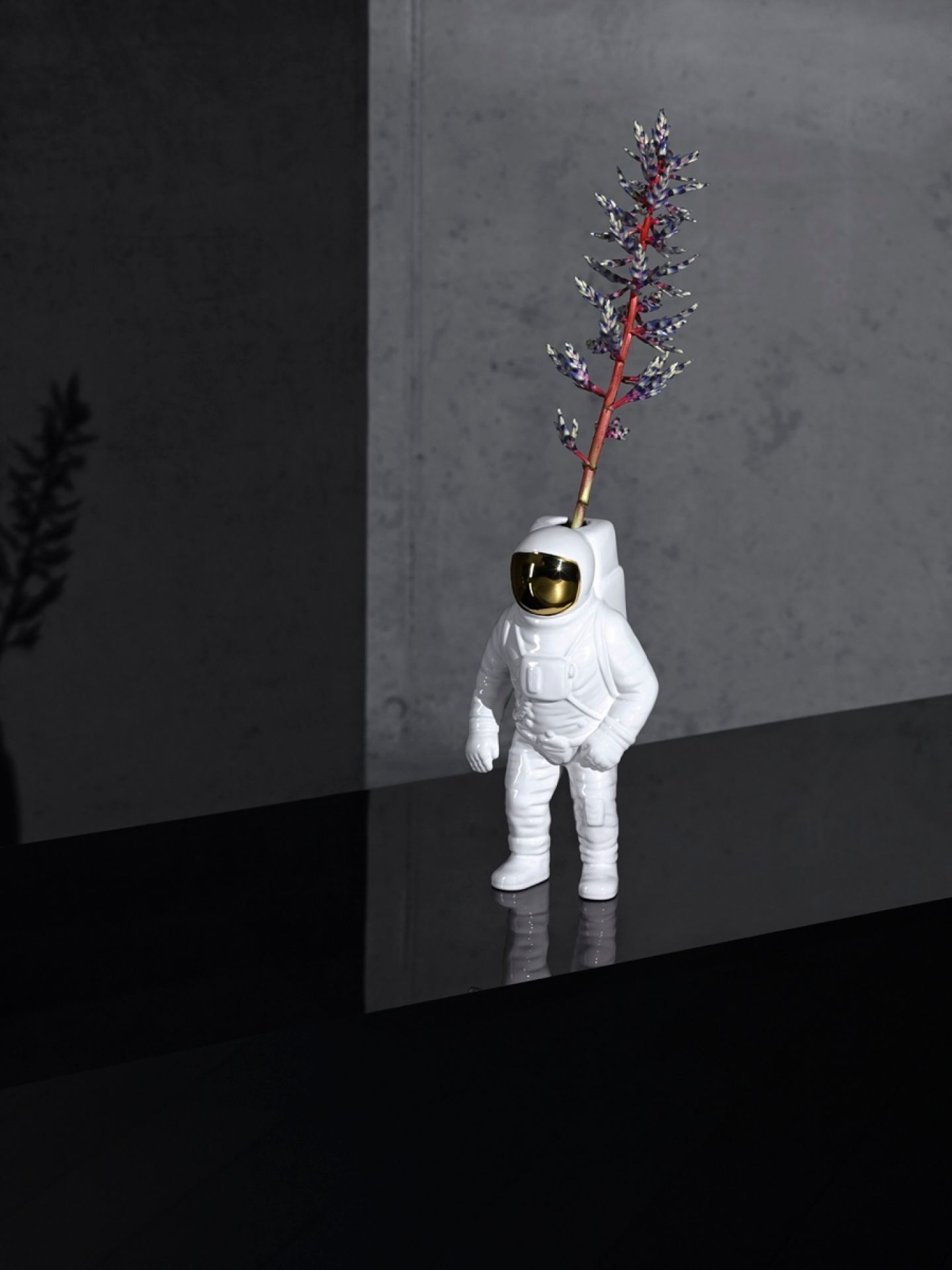 Weiße Starman Vase von Seletti in Form eines Astronauten mit Blume auf einem schwarzen Tisch.