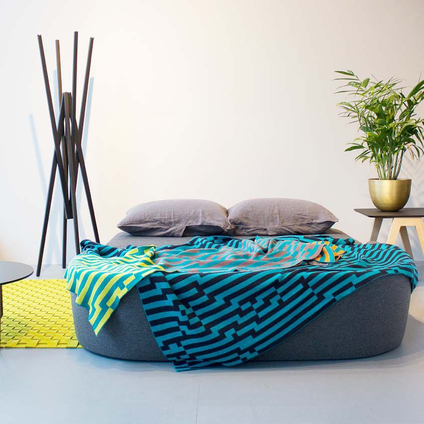 Up-lift Schlafsofa von Prostoria, graues modernes Sofa mit Kissen und bunter Decke im Wohnzimmer.