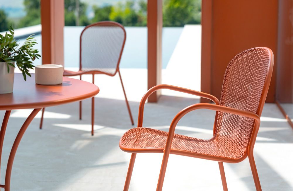 Nahaufnahme eines orangefarbenen Ronda Stuhls von Emu für den Außenbereich mit passendem Tisch.
