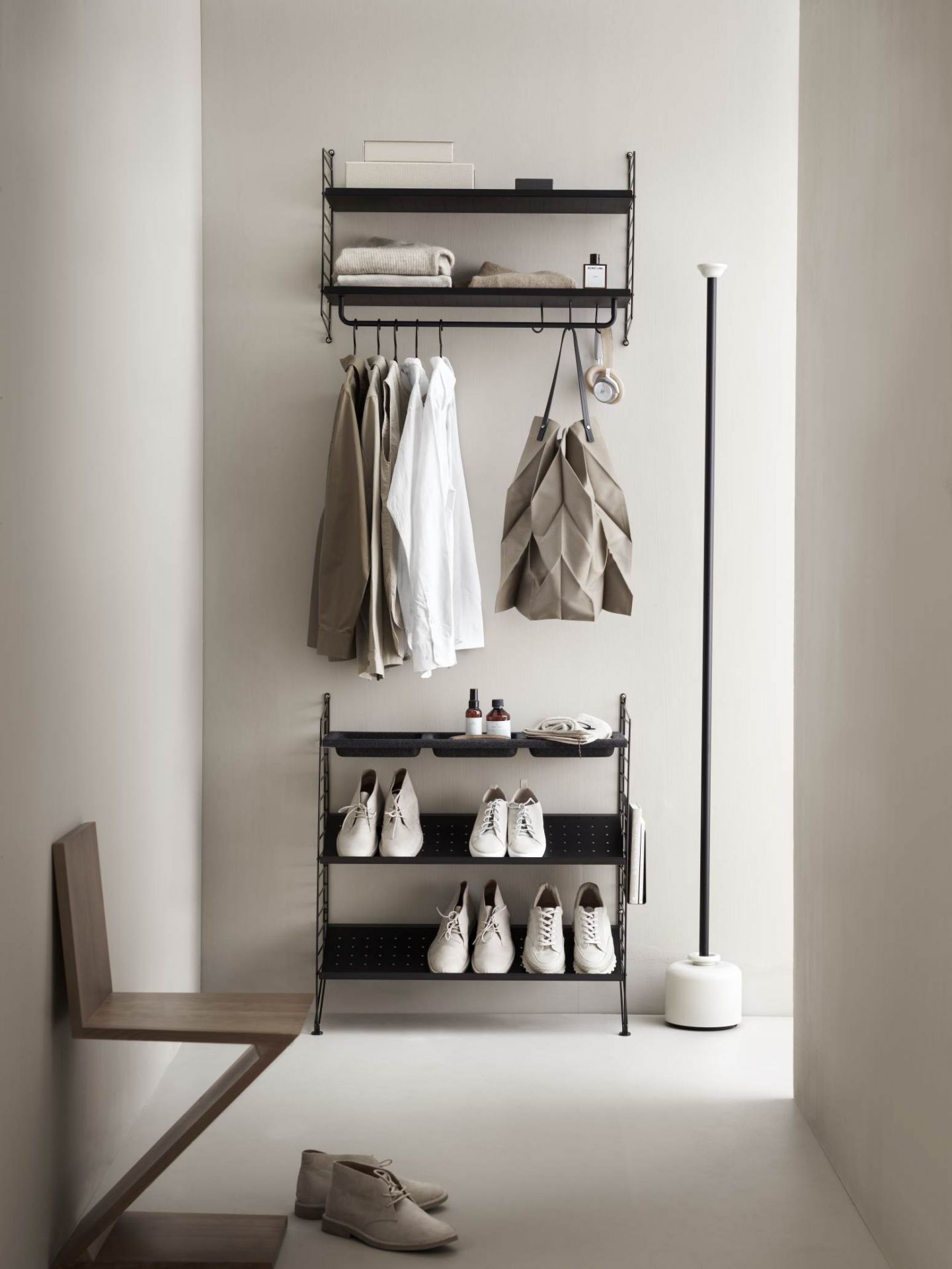 Schwarzes String Regalsystem im Flur mit Kleidung, Schuhen und Accessoires. Wandregal für Ordnung.