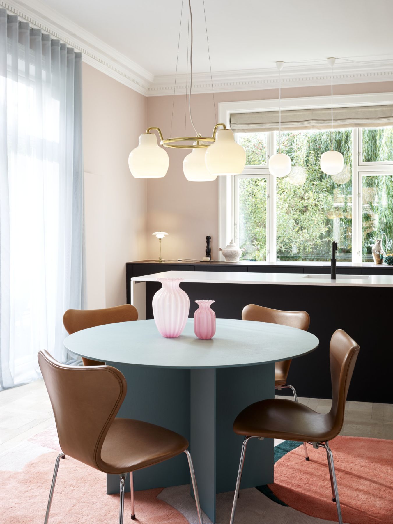 Esszimmer mit VL Ring Crown Pendelleuchte von Louis Poulsen über rundem Tisch mit Design-Stühlen.