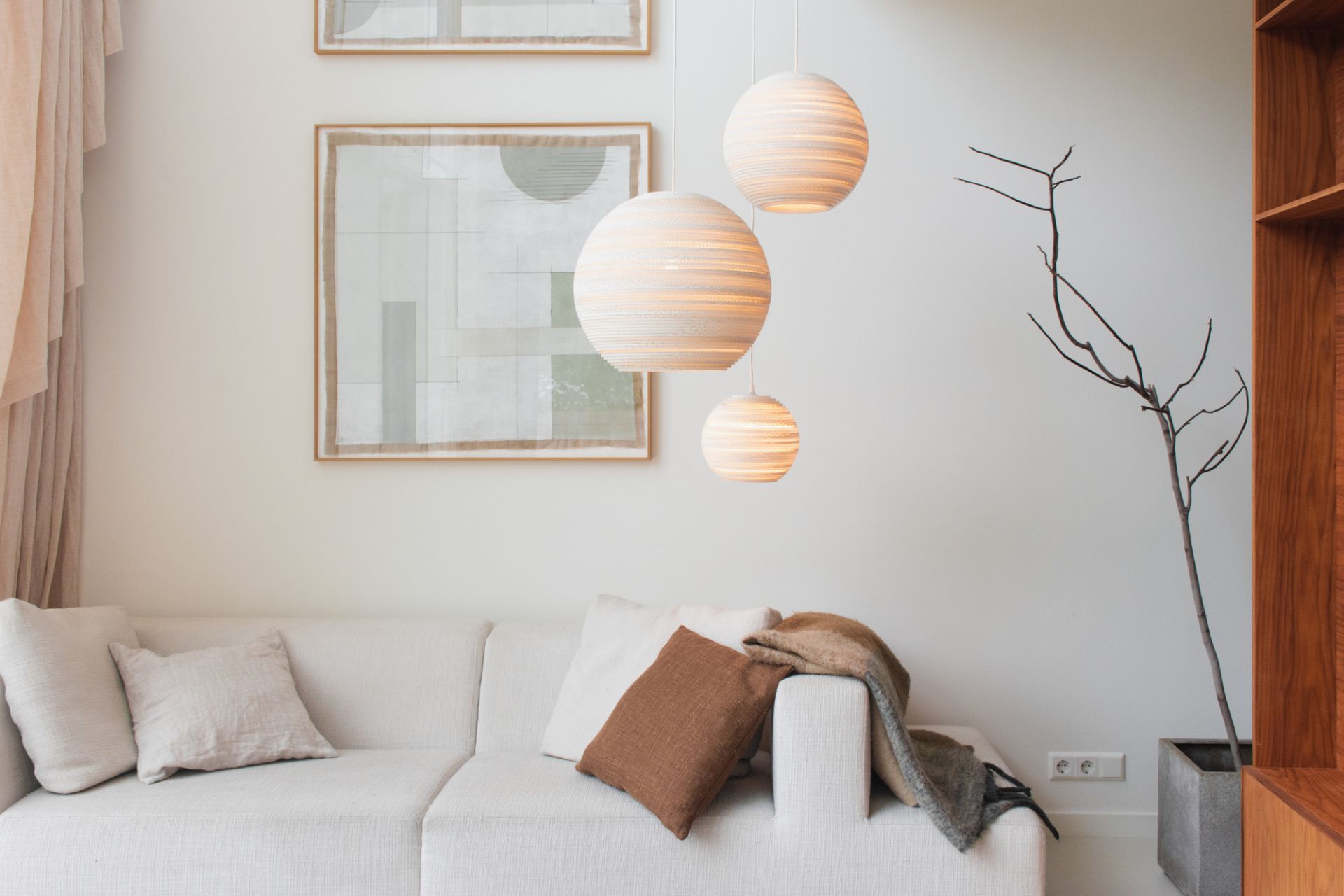 Graypants Scraplights Moon Hängeleuchten in verschiedenen Größen über einem weißen Sofa im Wohnzimmer.