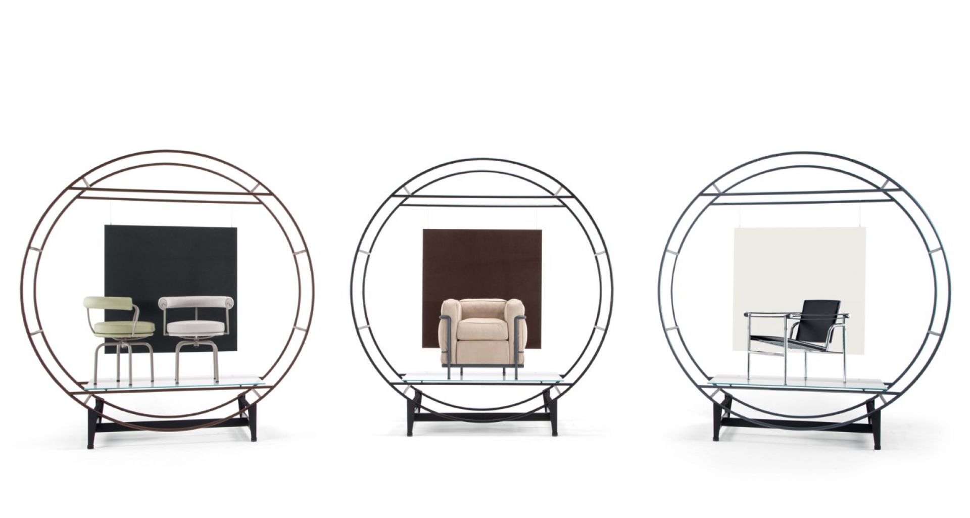 Drei Cassina 7 Fauteuil Tournant Drehsessel in verschiedenen Ausführungen, präsentiert in runden Metallrahmen auf Glasablagen.