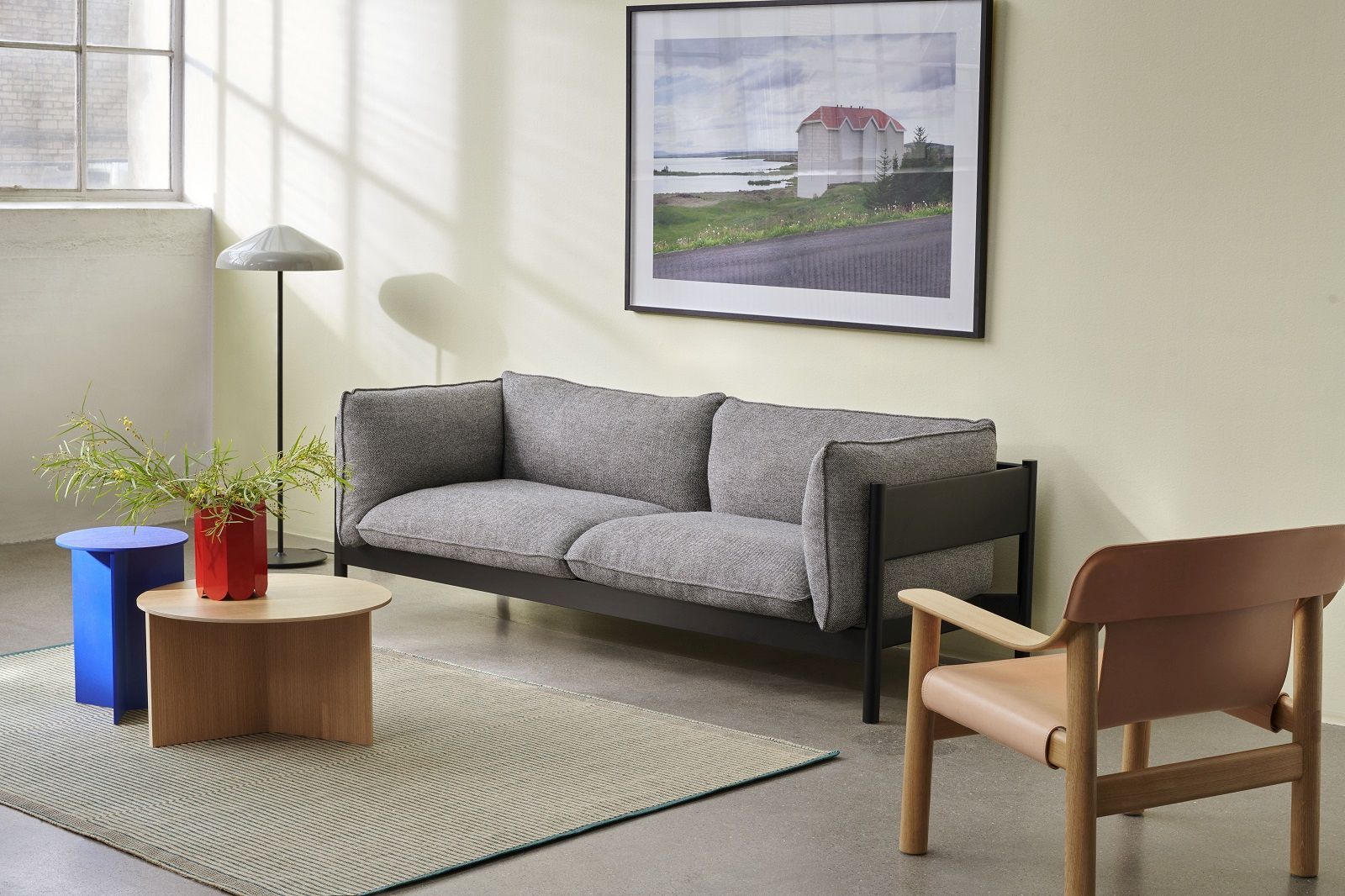 Heller Wohnraum mit Hay Slit Table Wood Round XL Beistelltisch aus Holz neben grauem Sofa.