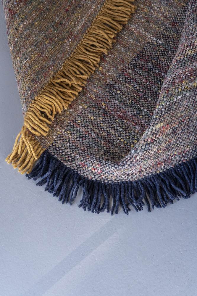 Detailaufnahme des Nanimarquina Re-Rug Teppichs mit Fransen in Gelb und Blau, gewebte Textur.