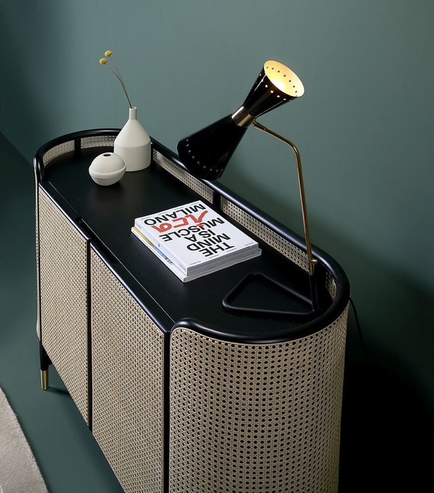 MOS CABINET Schrank von Wiener GTV Design mit schwarzer Oberfläche und Wiener Geflecht, darauf Lampe, Buch und Deko.