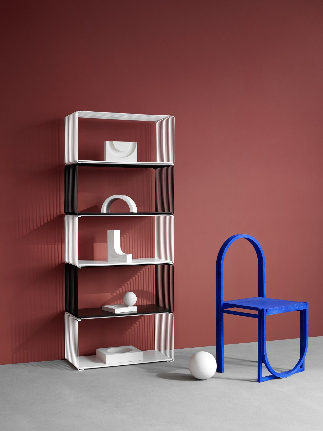 Panton Wire Regalsystem in Weiß und Schwarz mit Deko-Elementen, daneben ein blauer Stuhl.