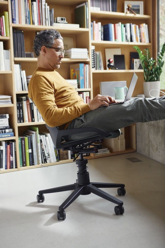 Mann sitzt entspannt mit Laptop auf dem ergonomischen Numo Bürodrehstuhl mit Rollen von Aeris.