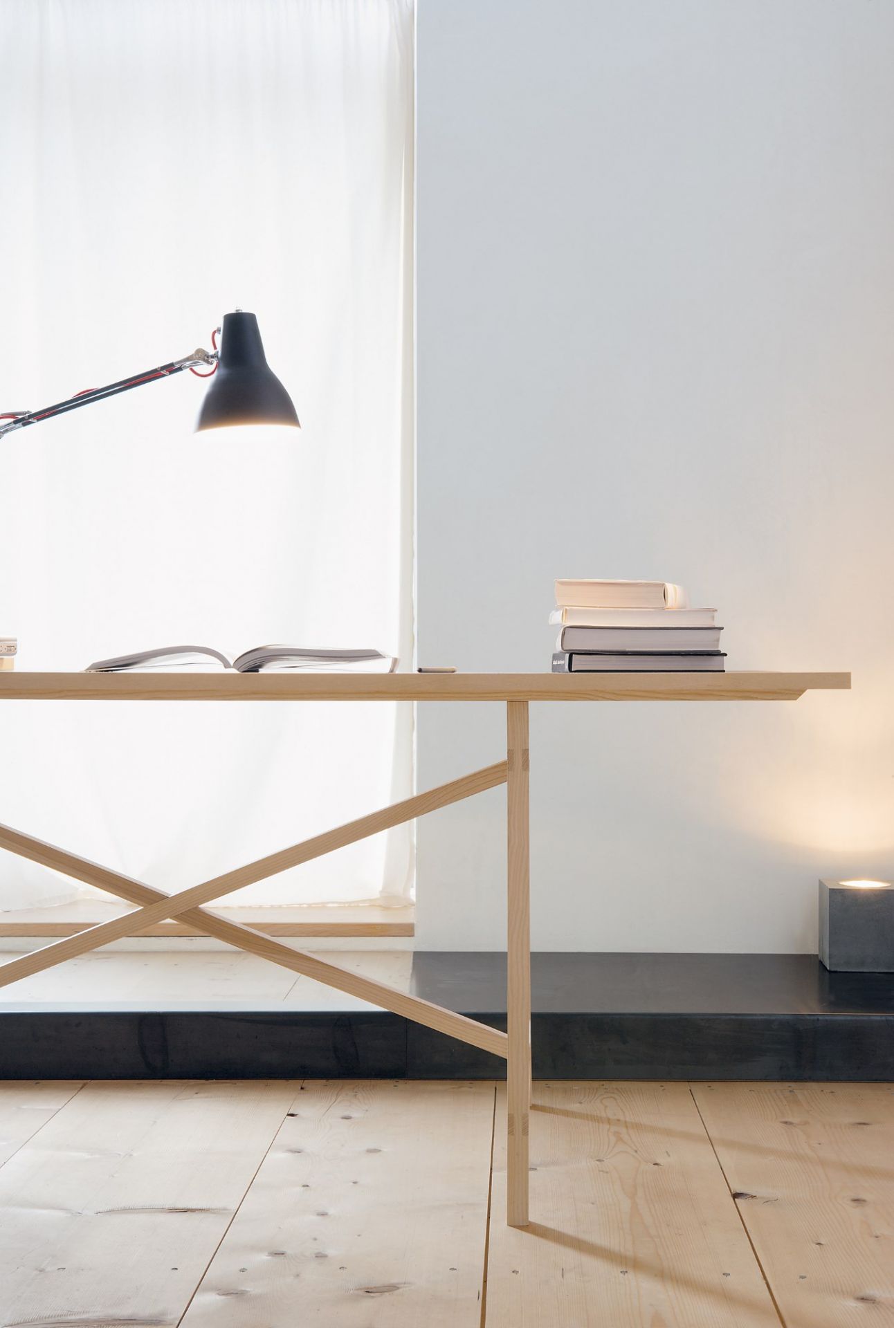 Egon Tisch von Nils Holger Moormann aus hellem Holz mit Lampe und Büchern.