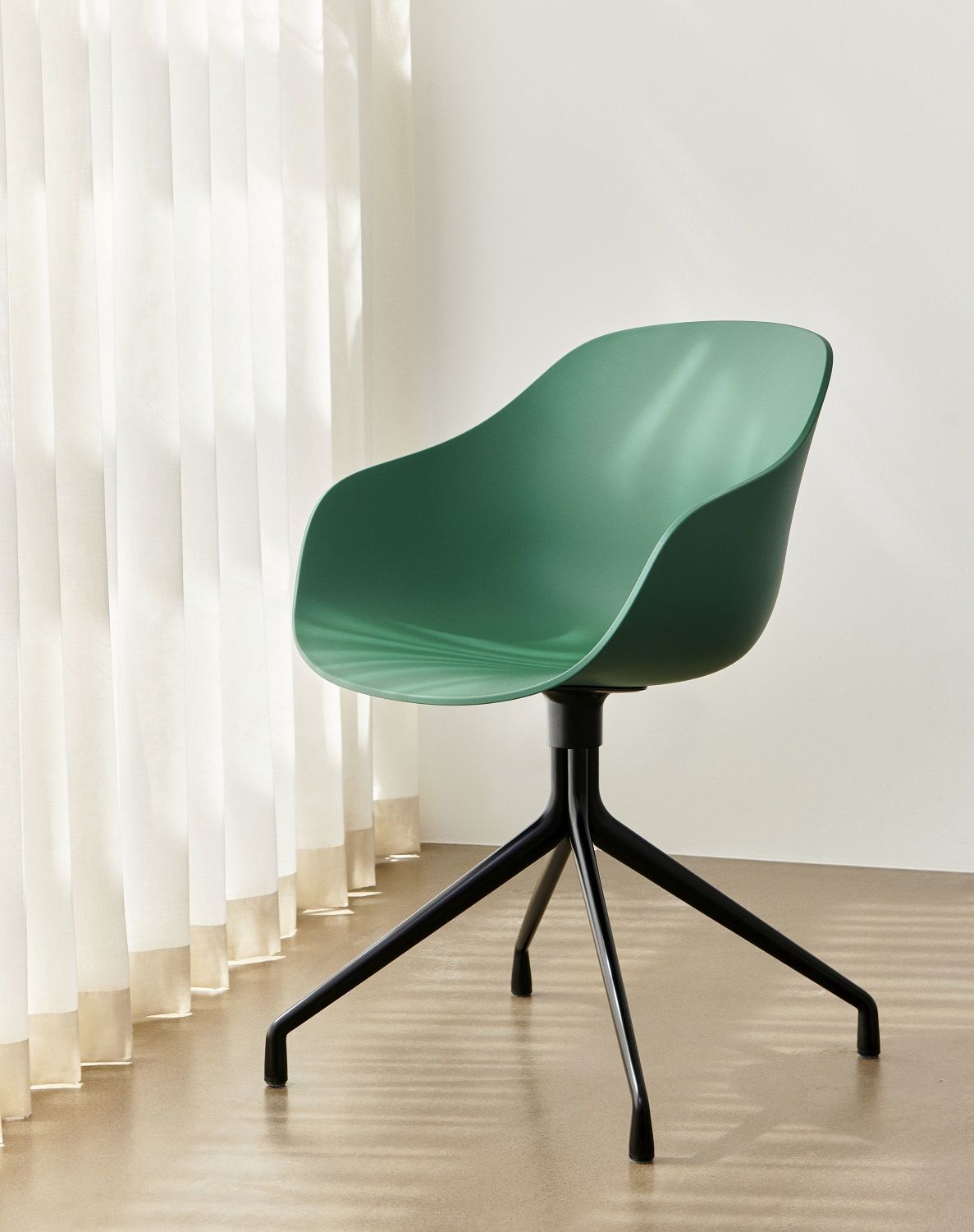 Grüner About a Chair AAC220 Stuhl von Hay mit schwarzem Vierfuß-Gestell vor Vorhang.