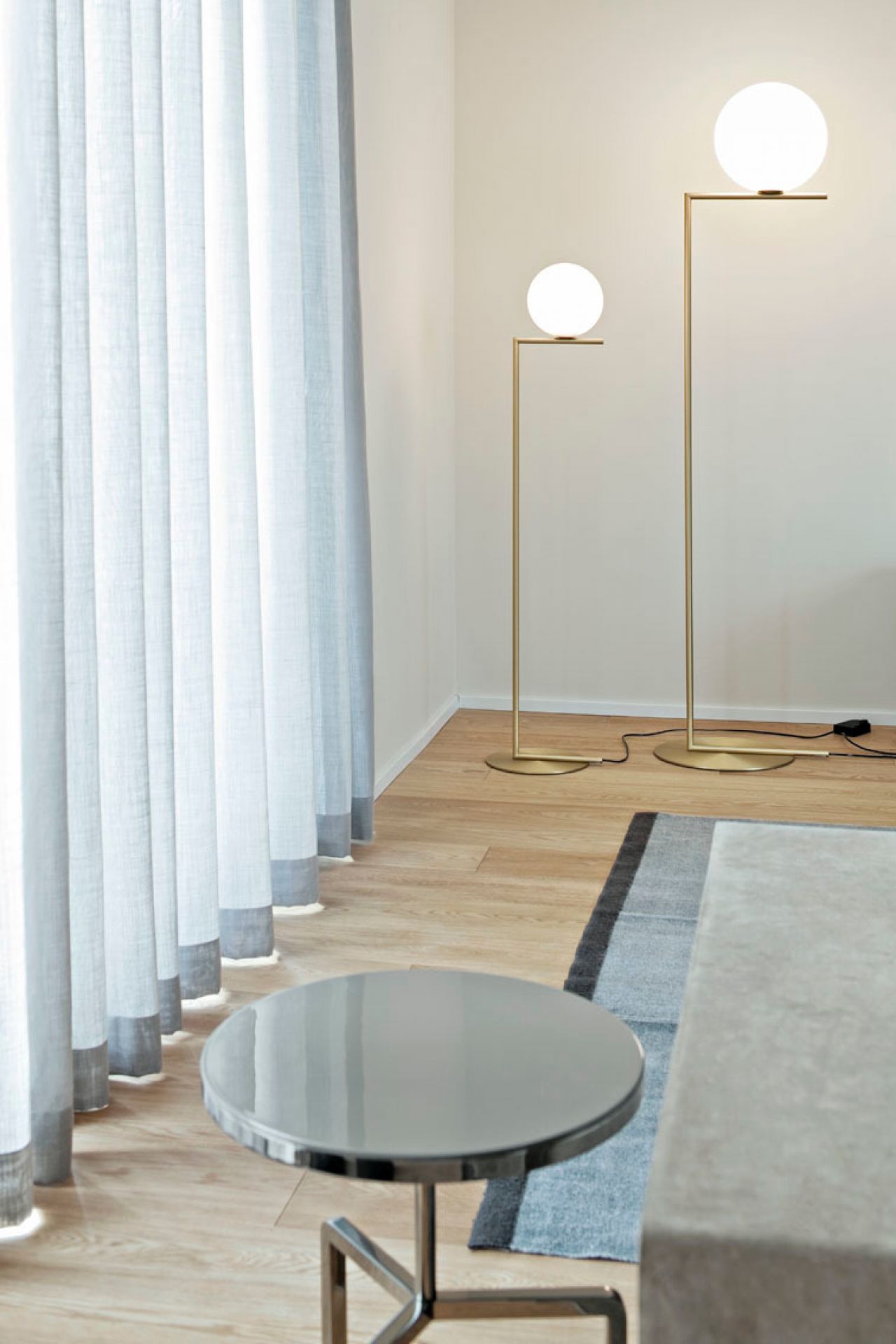 Zwei IC Lights Stehleuchten von Flos in Messing mit runden, weißen Lampenschirmen.