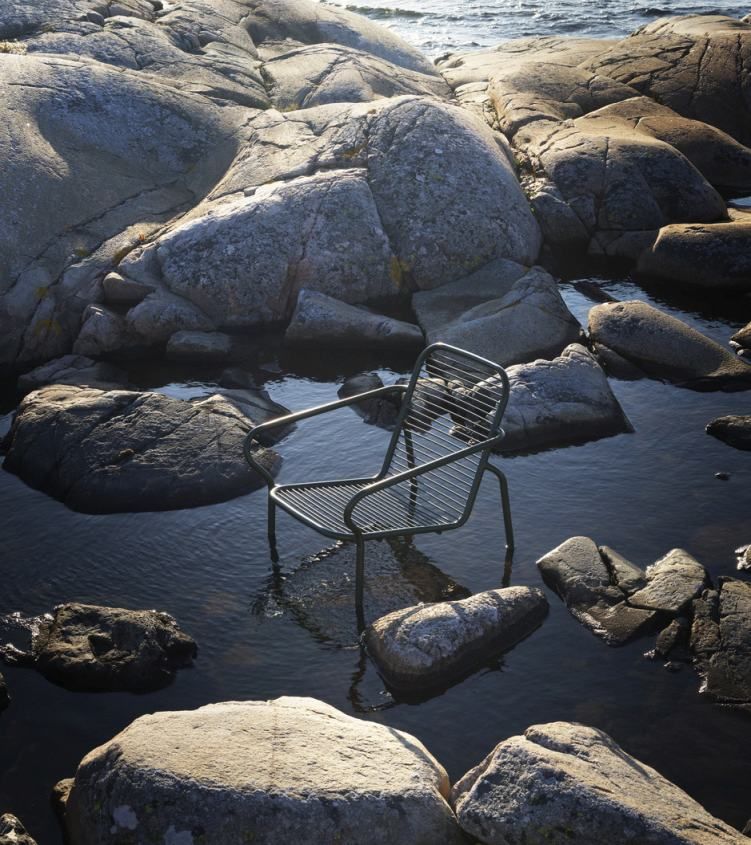 Normann Copenhagen Vig Lounge Chair Outdoor Sessel zwischen Felsen und Wasser, modernes Outdoor-Möbeldesign.