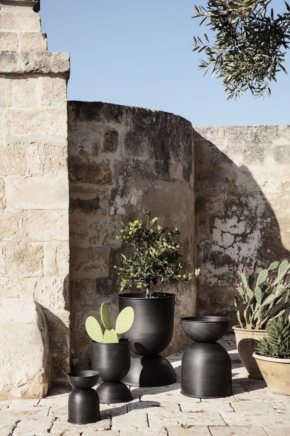 Schwarzer Hourglass Topf klein von Ferm Living mit Pflanzen im Außenbereich. Design Pflanzgefäß.