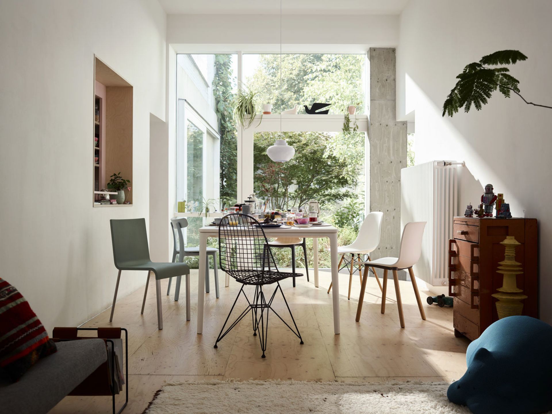 Esszimmer mit Esstisch und verschiedenen Stühlen, darunter ein schwarzer Drahtstuhl und ein .03 Stuhl von Vitra.