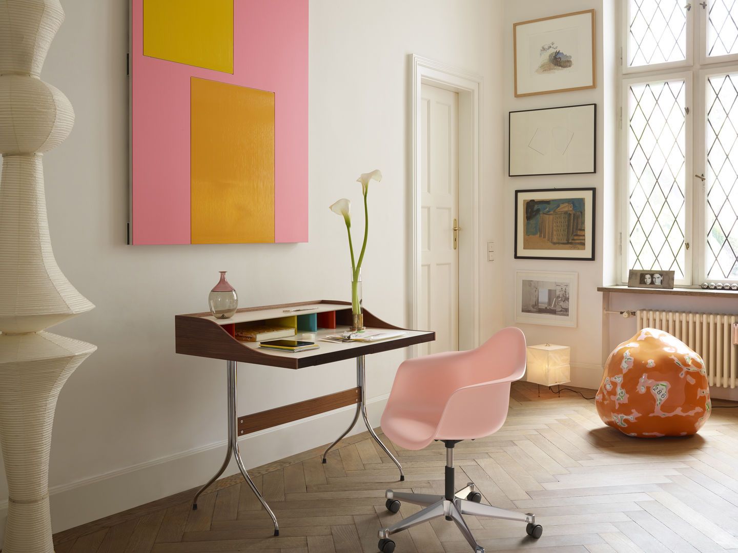Rosa Eames Plastic Arm Chair PACC Stuhl von Vitra am Schreibtisch in einem stilvollen Wohnraum.