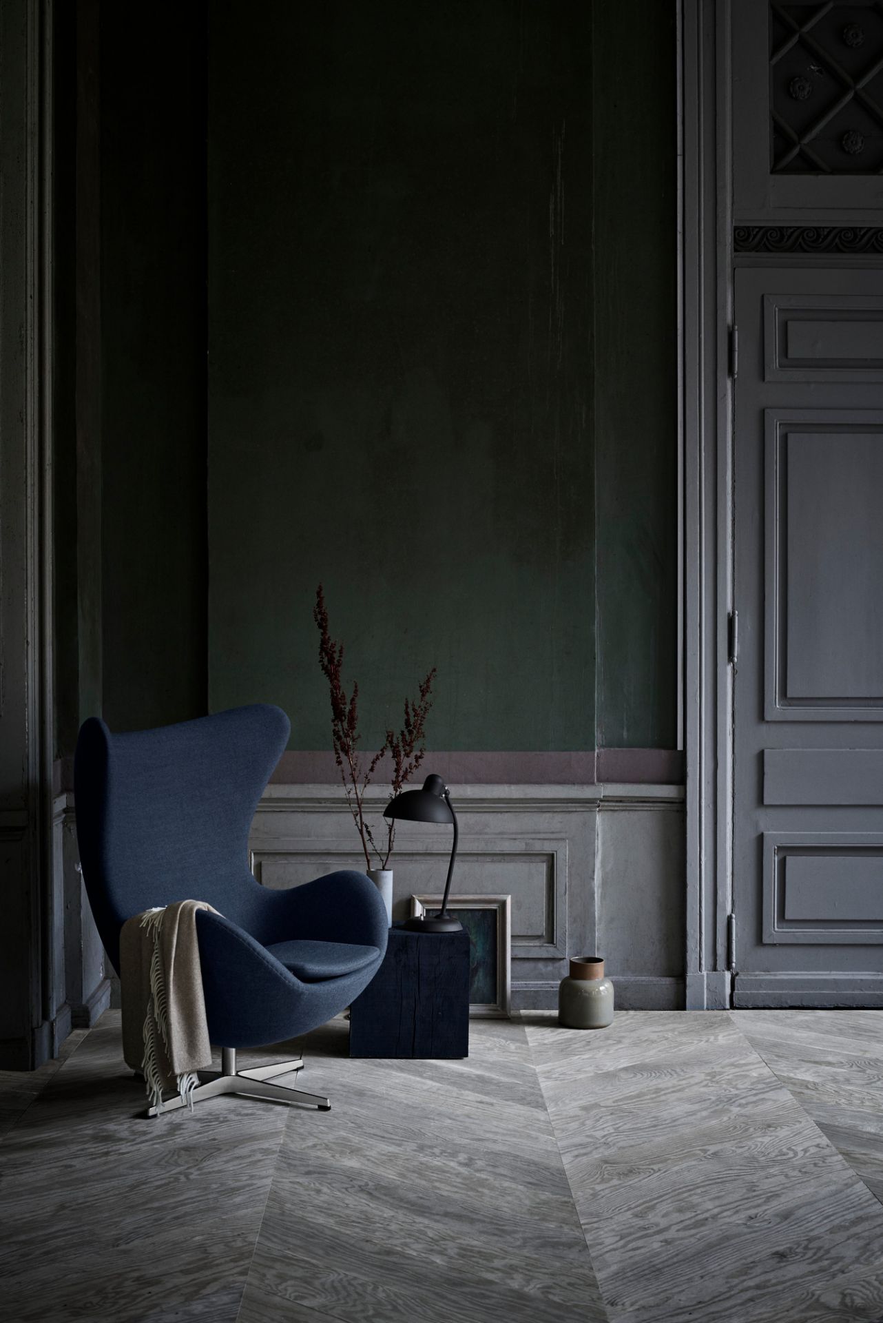 Olivgrüne KAISER idell 6556 T Tischleuchte neben Sessel in stilvollem Interieur. Design Lampe.