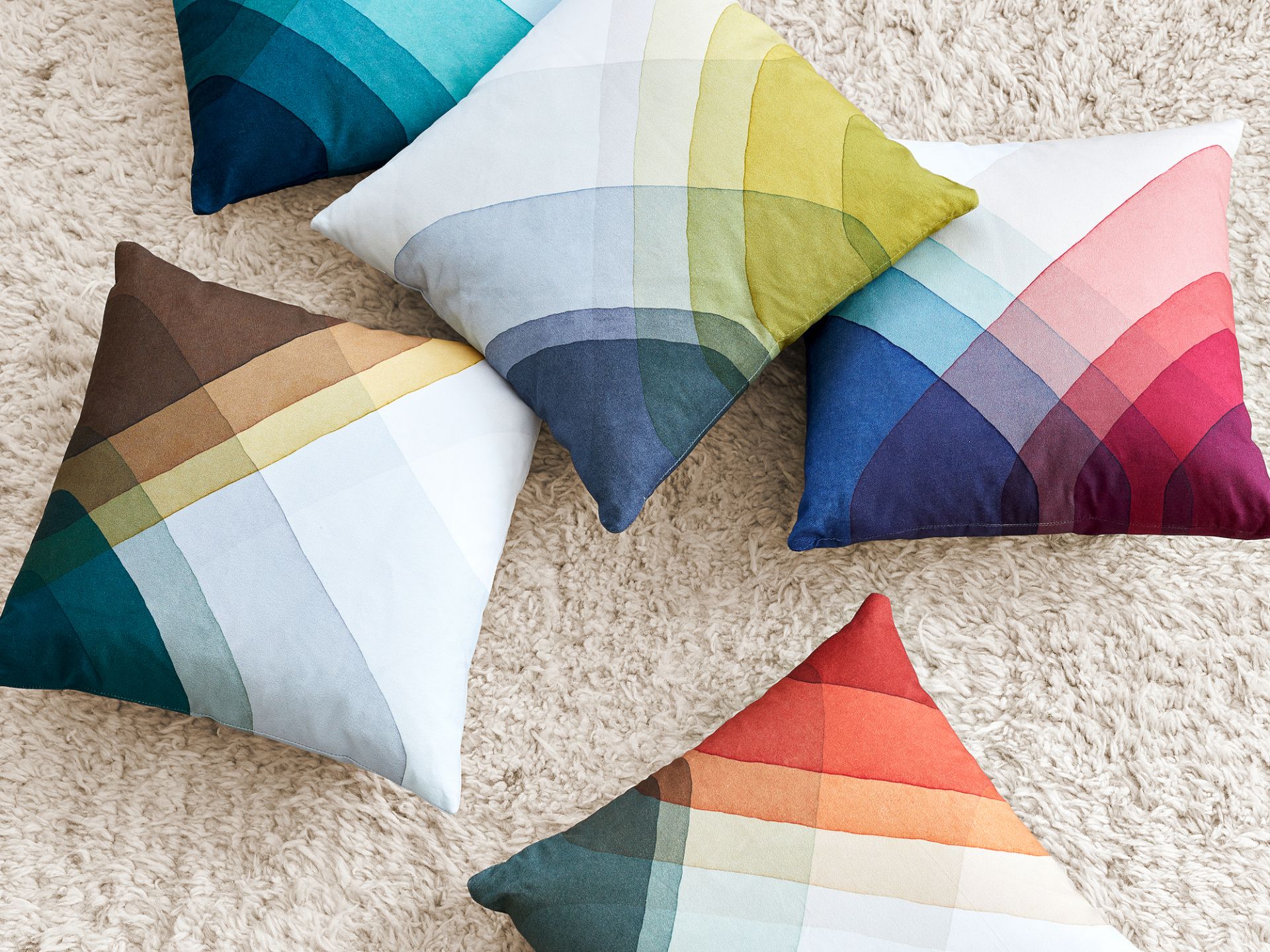 Mehrere bunte Heringbone Pillows Kissen von Vitra auf einem beigen Teppich, Dekokissen mit Farbverlauf.