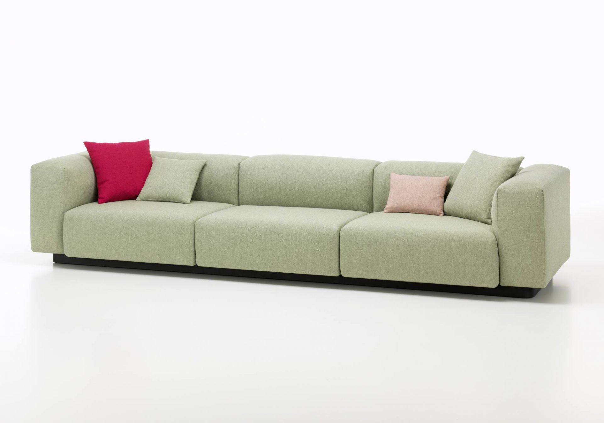 Vitra Soft Modular Sofa Dreisitzer in Hellgrün mit roten und rosa Kissen auf weißem Hintergrund.
