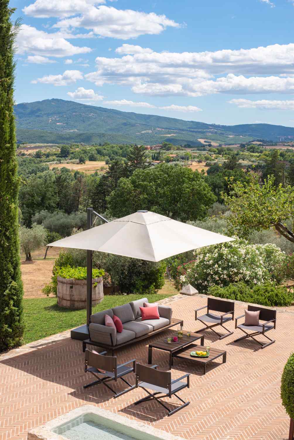 Terra Emu Outdoor-Möbel: Fußhocker, Sofa, Sessel und Tische auf einer Terrasse mit Blick in die Landschaft.