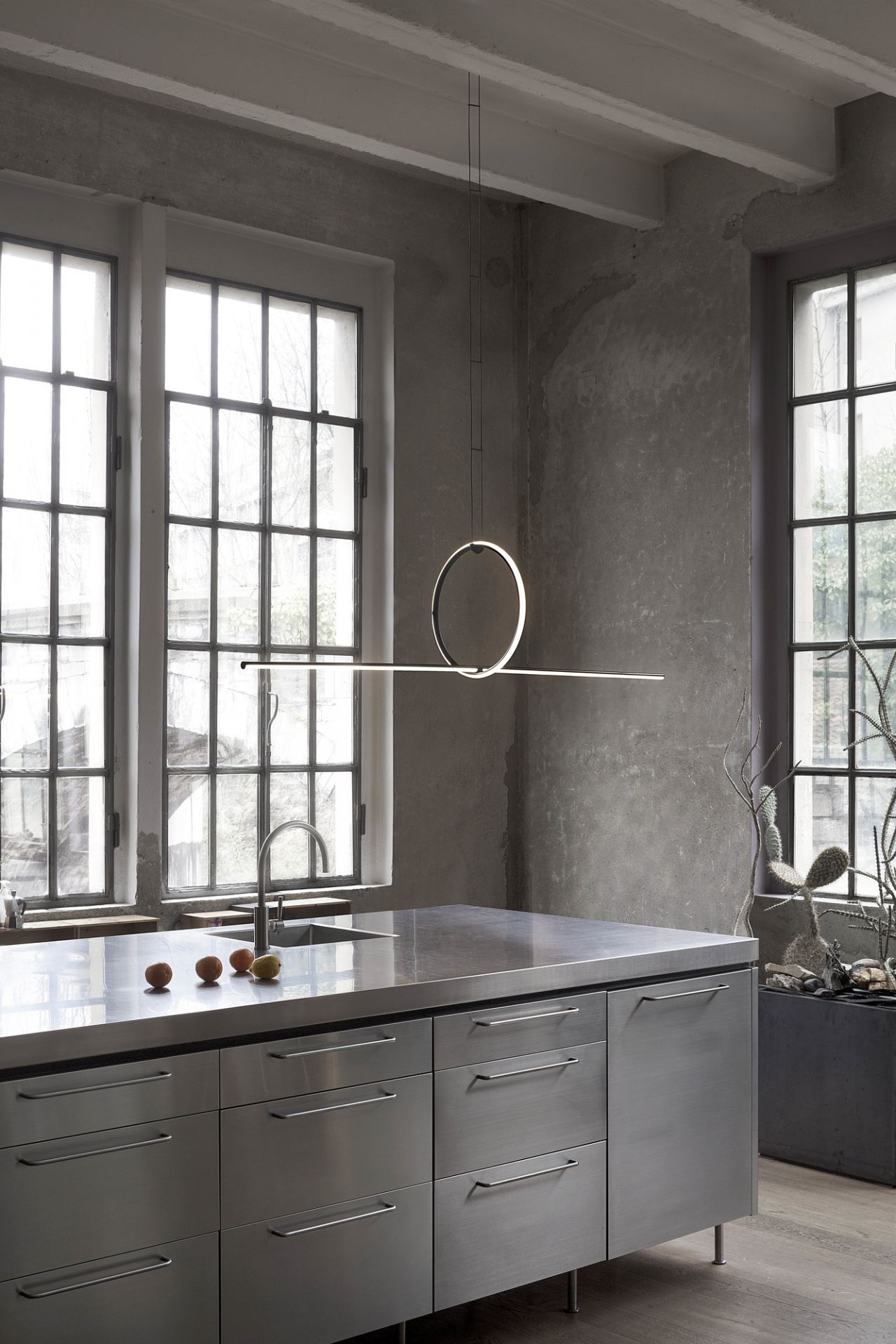 Flos Arrangements Pendelleuchte in moderner Küche mit Edelstahlinsel und großen Fenstern für stilvolle Beleuchtung.