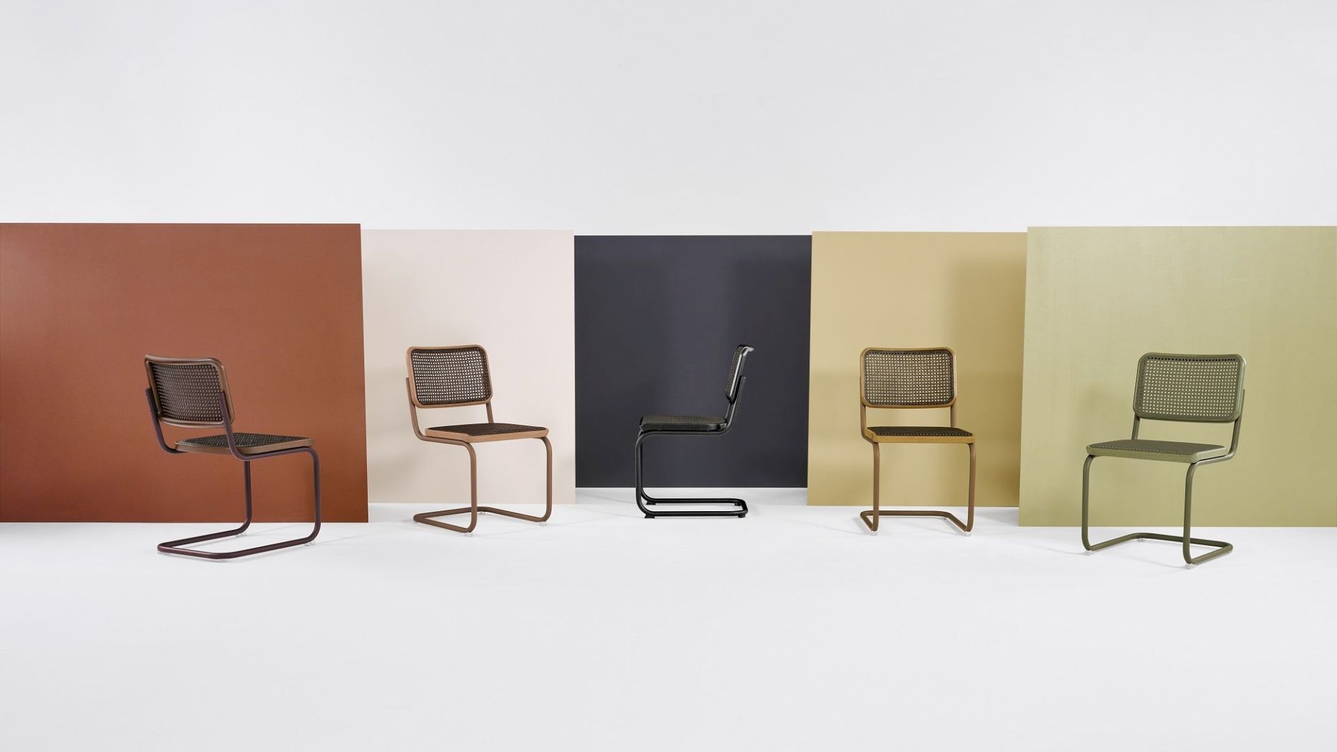 Fünf S 32 V Stahlrohr Freischwinger Thonet Stühle in verschiedenen Farben vor farbigen Hintergründen.