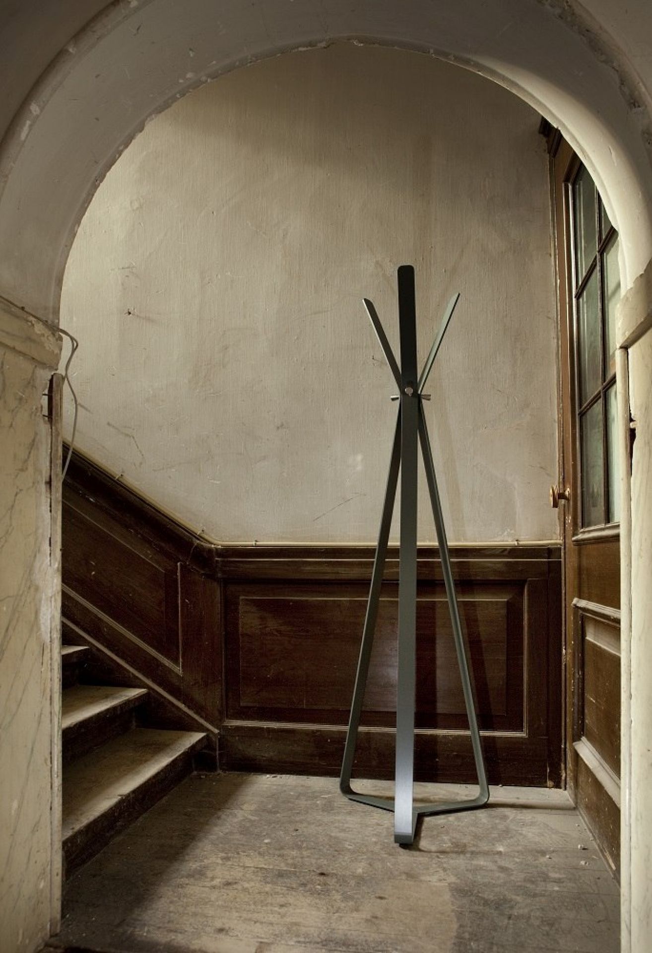 Moderne, graue Kleiderständer Garderobe aus Metall im Flur eines Altbaus mit Treppe und Holztür.