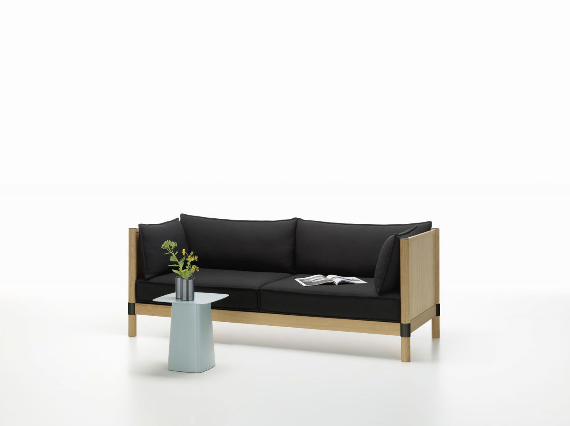 Blauer Metal Side Table Beistelltisch Medium von Vitra neben Sofa mit Blumen.