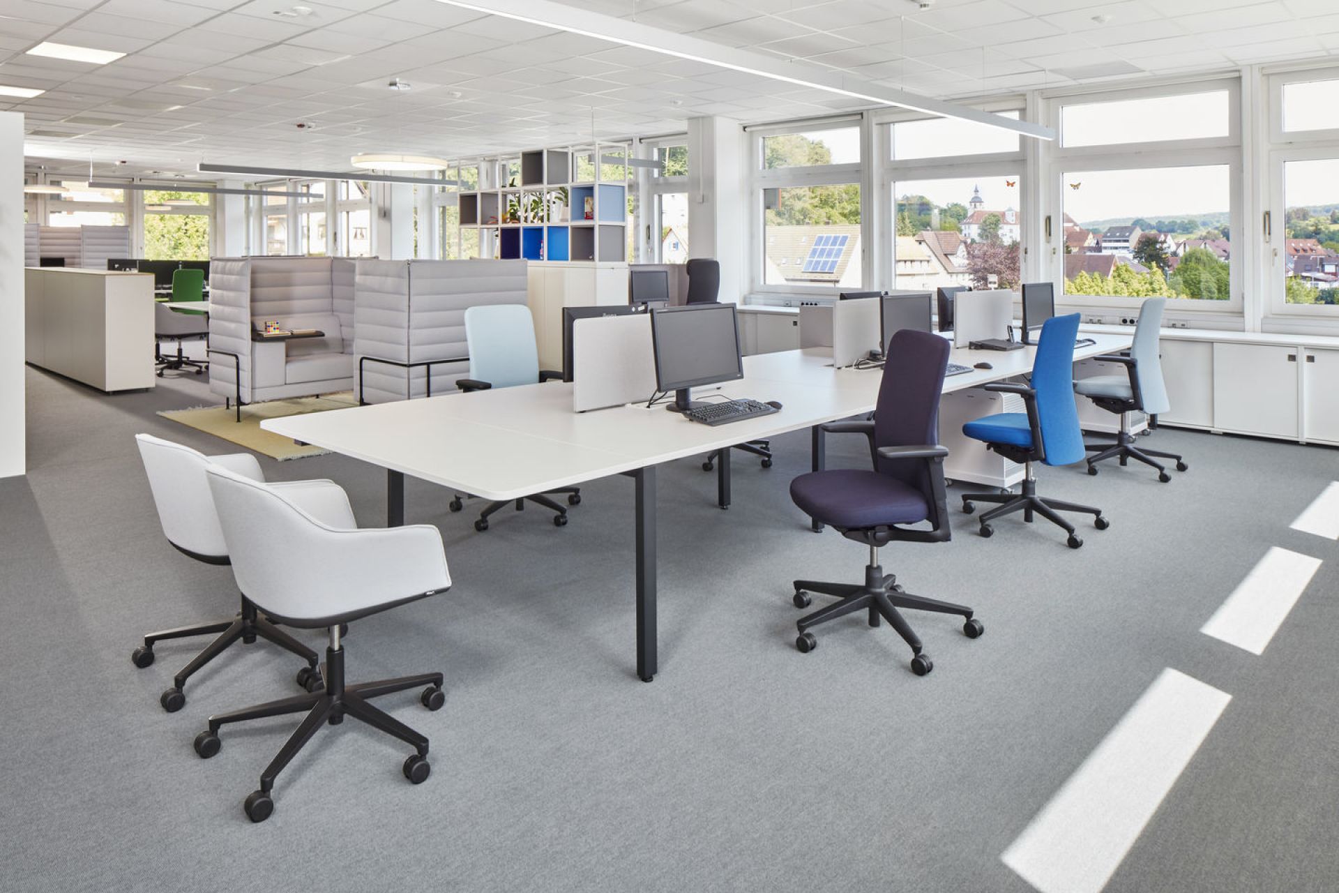 Büro mit Softshell Chair von Vitra, Drehstühle in verschiedenen Farben und langen Schreibtischen.