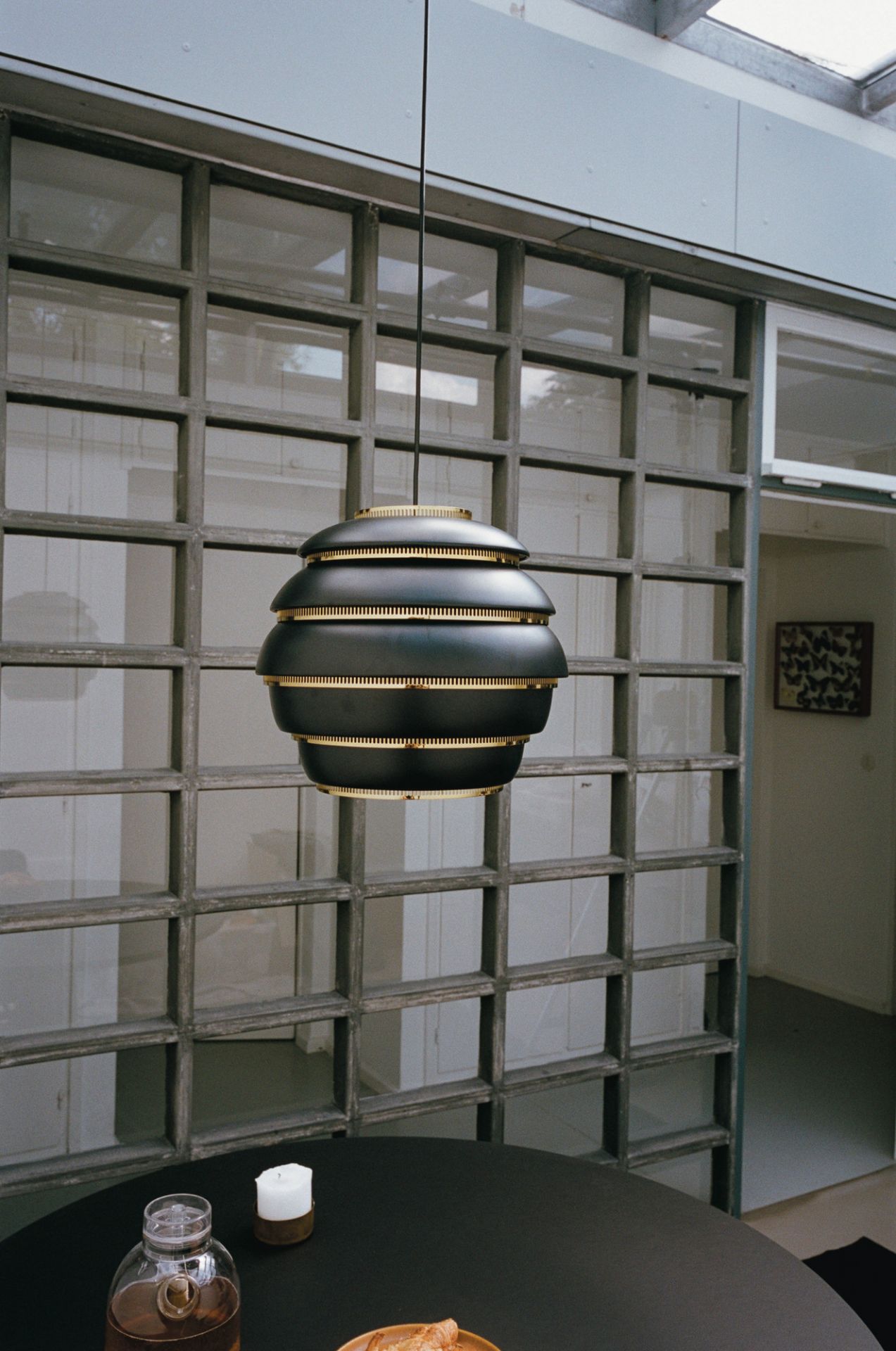 A331 Beehive Hängeleuchte von Artek in Schwarz über einem Esstisch mit Getränken und Kerze.
