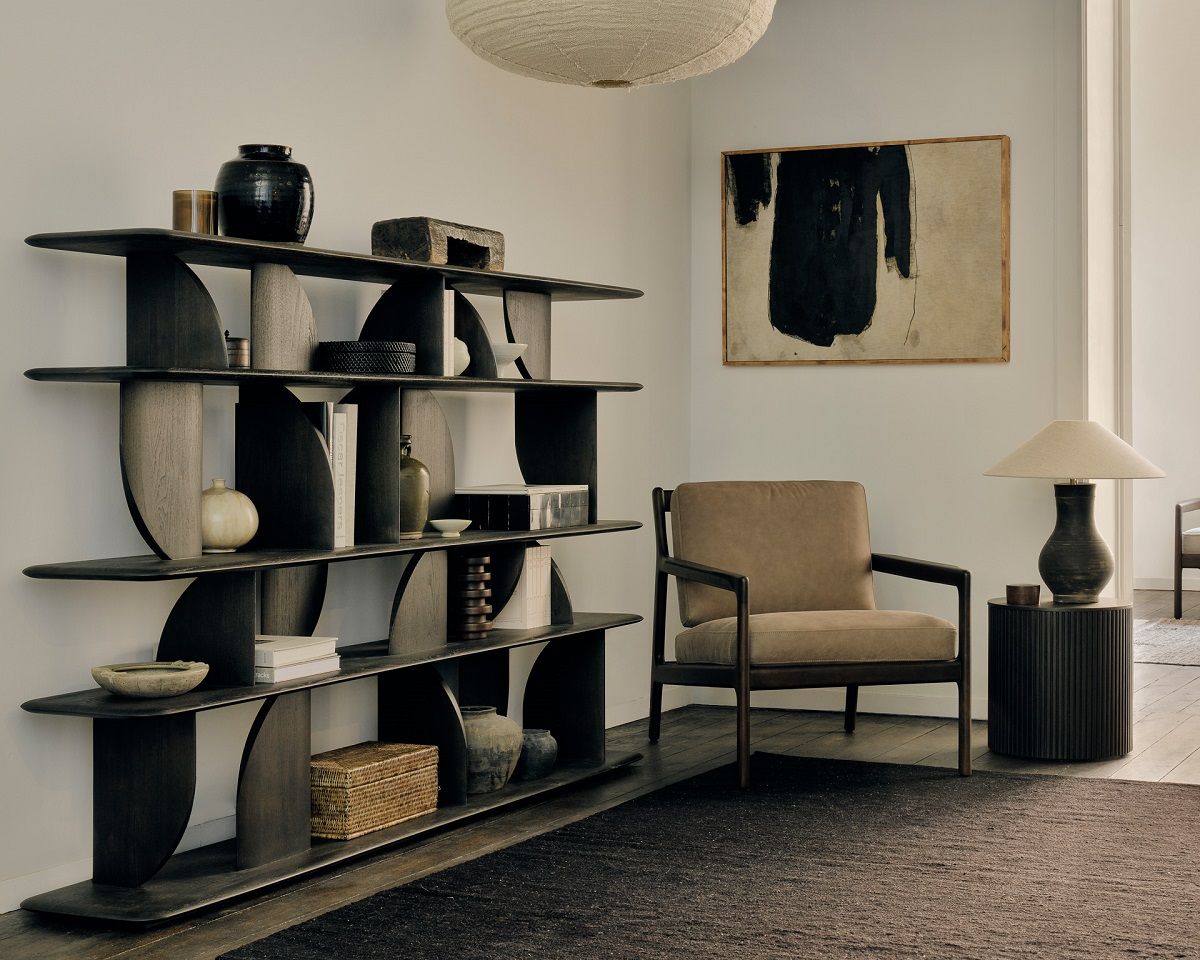 Lackiertes Ethnicraft Teak Regal "Geometric" im Wohnzimmer mit Deko-Objekten, Sessel und Lampe.
