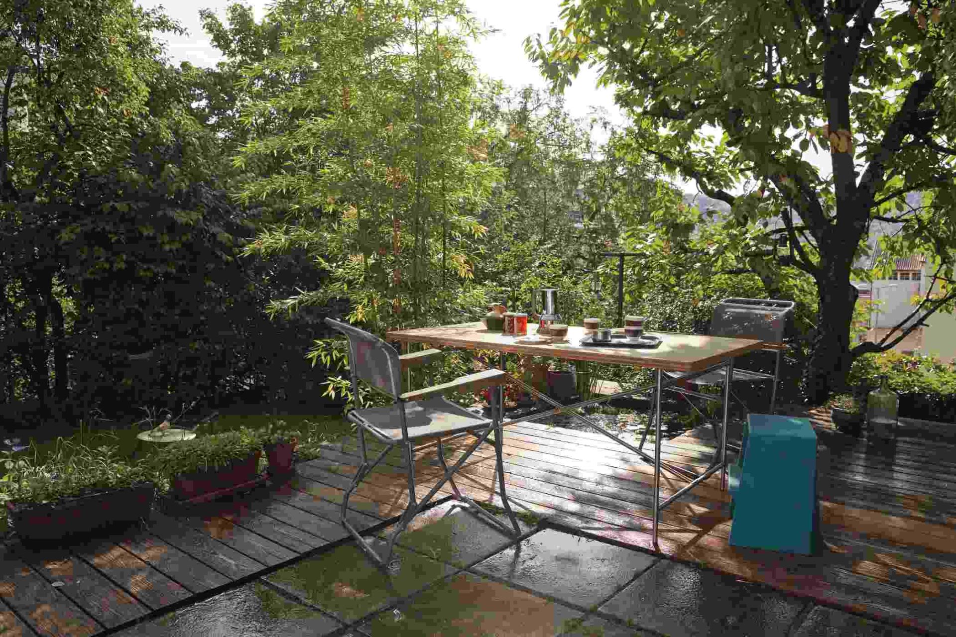 Eiermann Tisch mit Stühlen auf einer Terrasse im Grünen, ideal für den Garten.