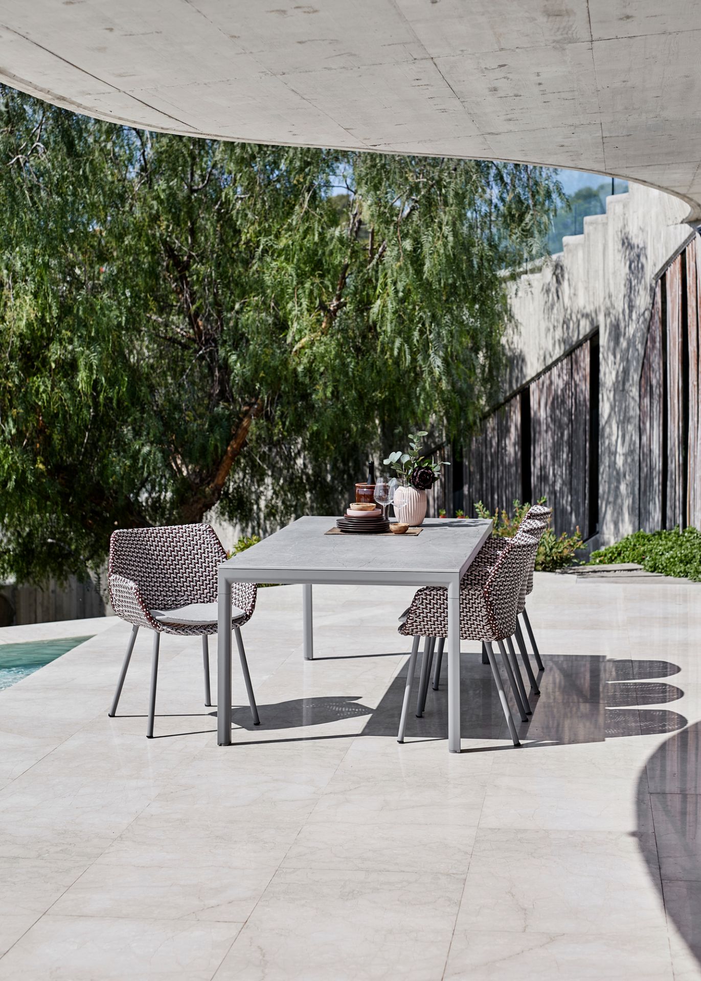 Cane-Line Vibe Outdoor Sessel mit Esstisch auf einer Terrasse, modernes Gartenmöbel-Set.