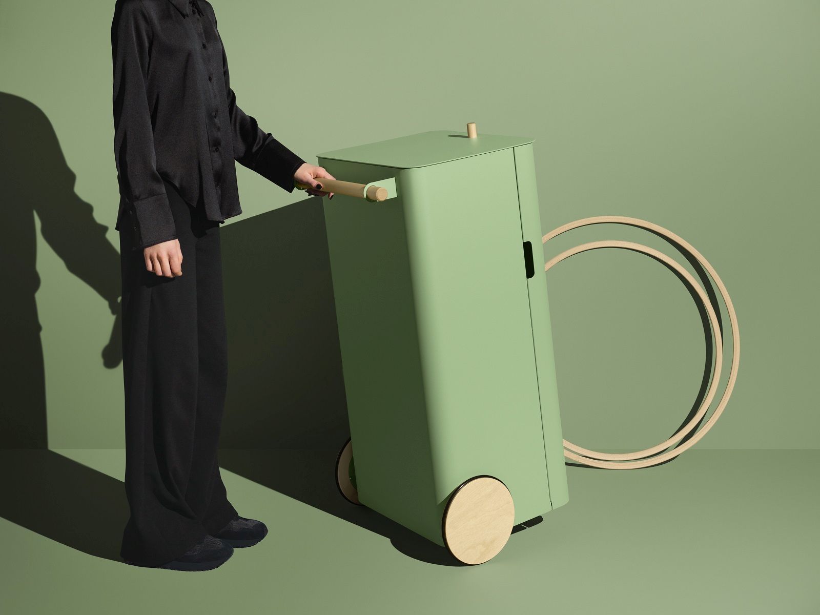 Arkityp Bin M: Moderner, mintgrüner Mülleimer zur Mülltrennung mit Holzrädern und Griff, bedient von einer Person.