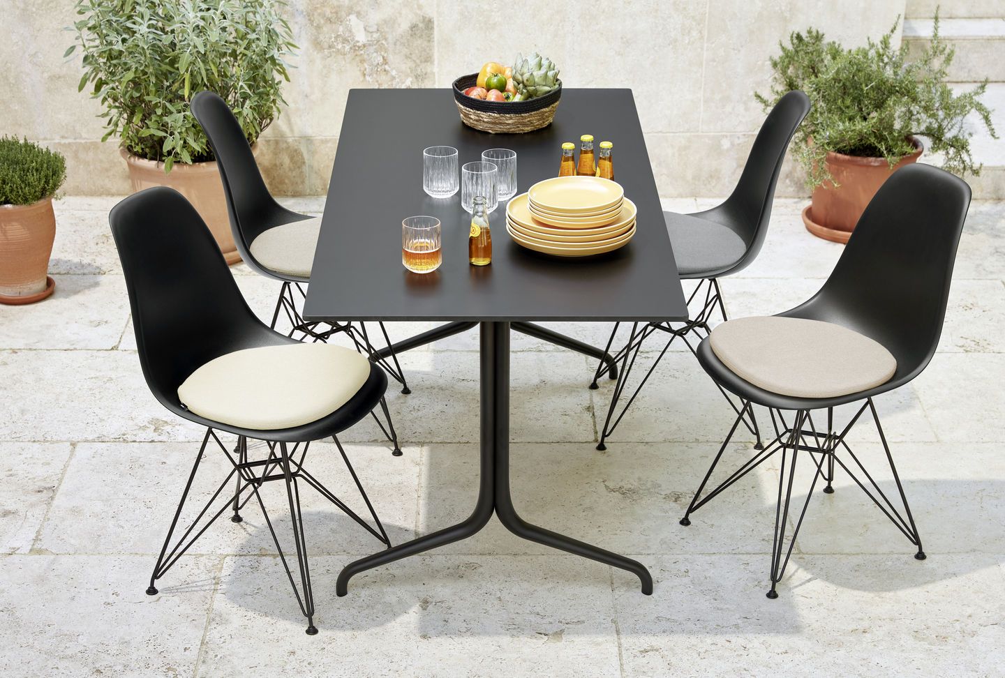 Eames Fiberglass Chair DSR Stuhl mit Sitzpolster von Vitra an Esstisch im Außenbereich.
