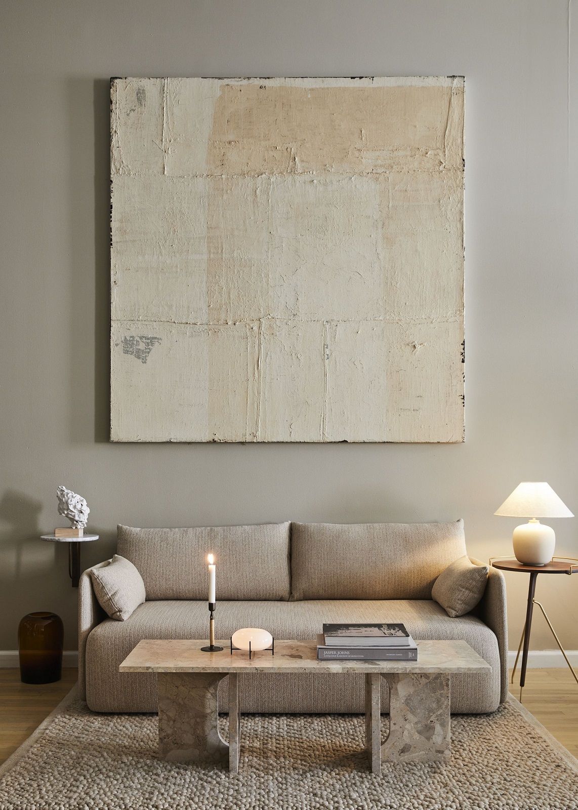 Beige Wohnzimmer-Szene mit Audo Copenhagen Gravel Rug Teppich, Sofa, Couchtisch und Kunstwerk an der Wand.