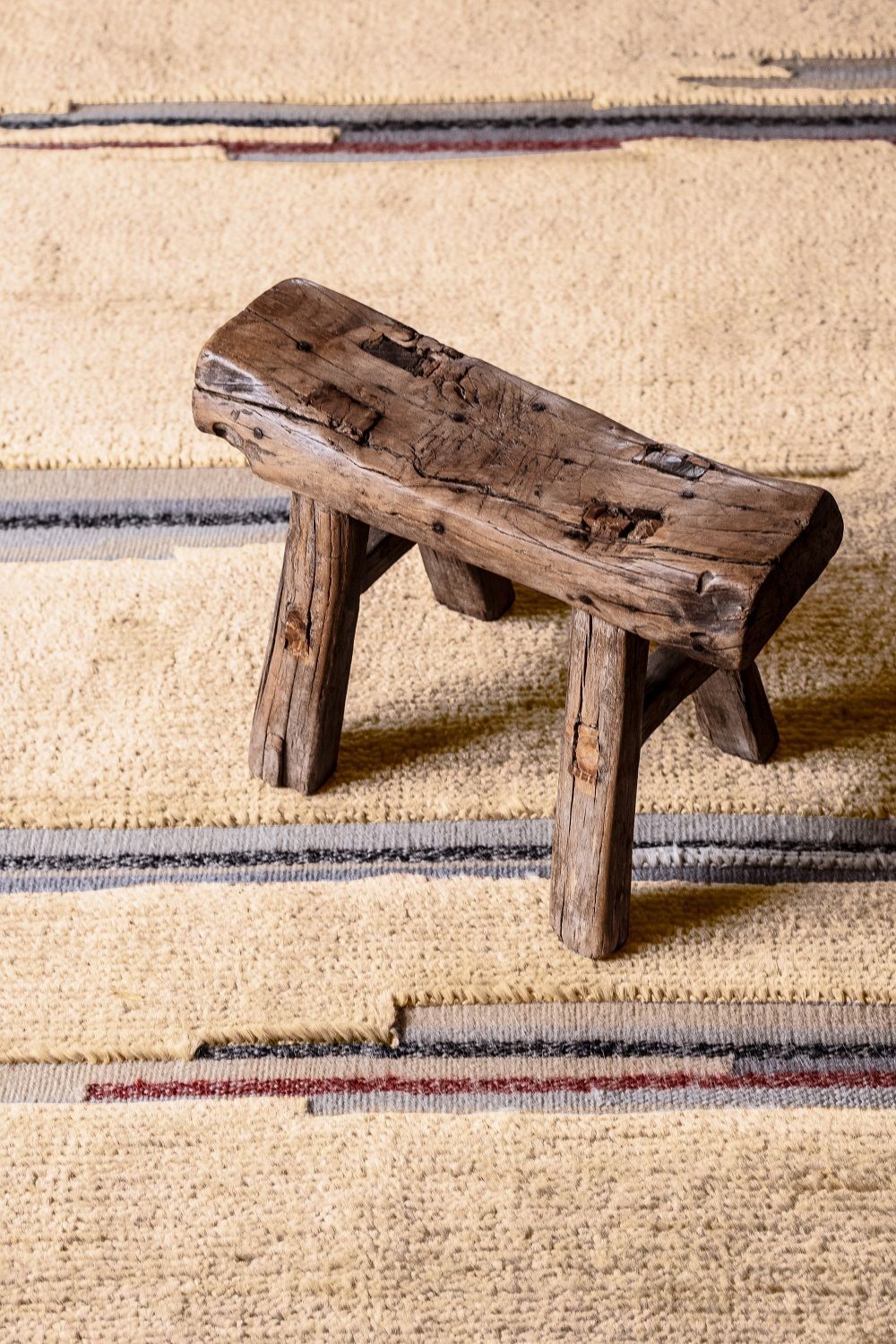 Nahaufnahme des Colorado Teppichs von Nanimarquina, ein beiger Wollteppich mit farbigen Streifen.