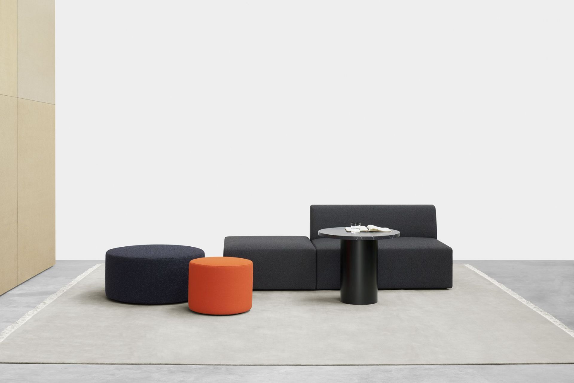 Enoki CT09 Beistelltisch von e15 mit grauer Couch, blauen und orangen Hockern auf einem Teppich.