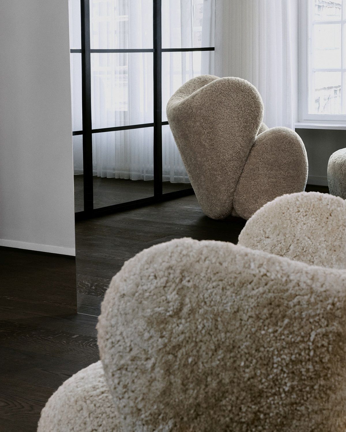 Nahaufnahme des NORR11 Big Big Lounge Sessels mit beigem Bouclé-Bezug in modernem Wohnambiente.